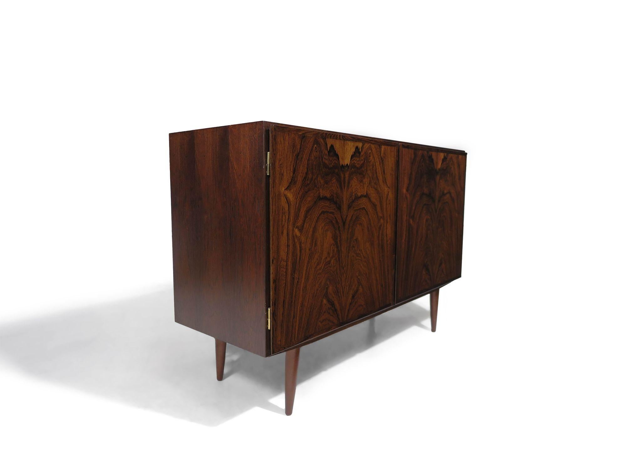 Brazilian rosewood cabinet designed by Omann Jun for Omann Jun Møbelfabrik, Denmark, 1964. This finely crafted cabinet features mitered corners and dynamic book-matched grain on the doors, and is raised on elegant tapered legs. The interior is