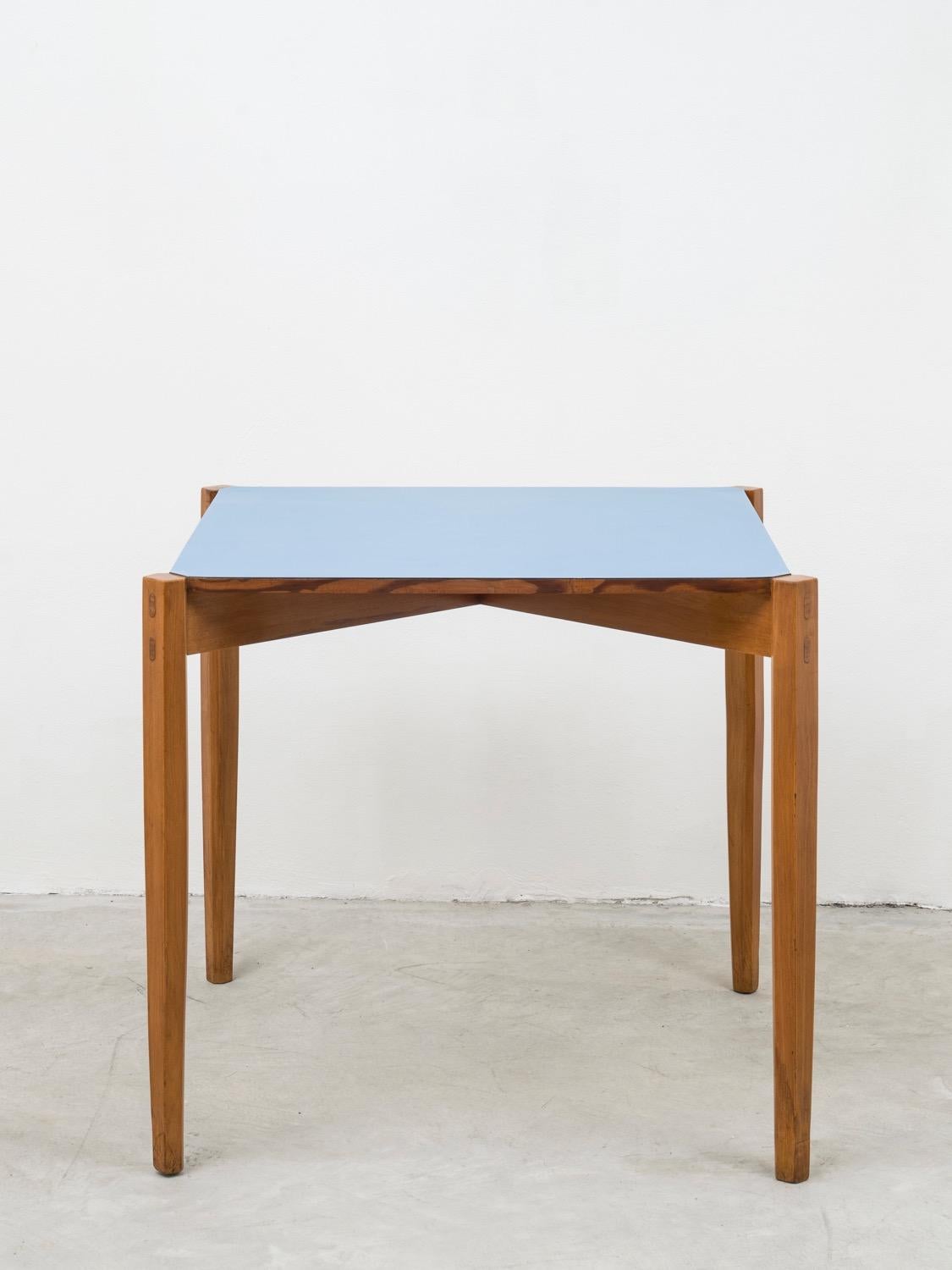 This outstanding square table, that could be used both as a gaming or dining table, is a unique piece, signed under the top, by artist and designer Giulio Alchini. The use of such a light blue formica together with wood resembles also several