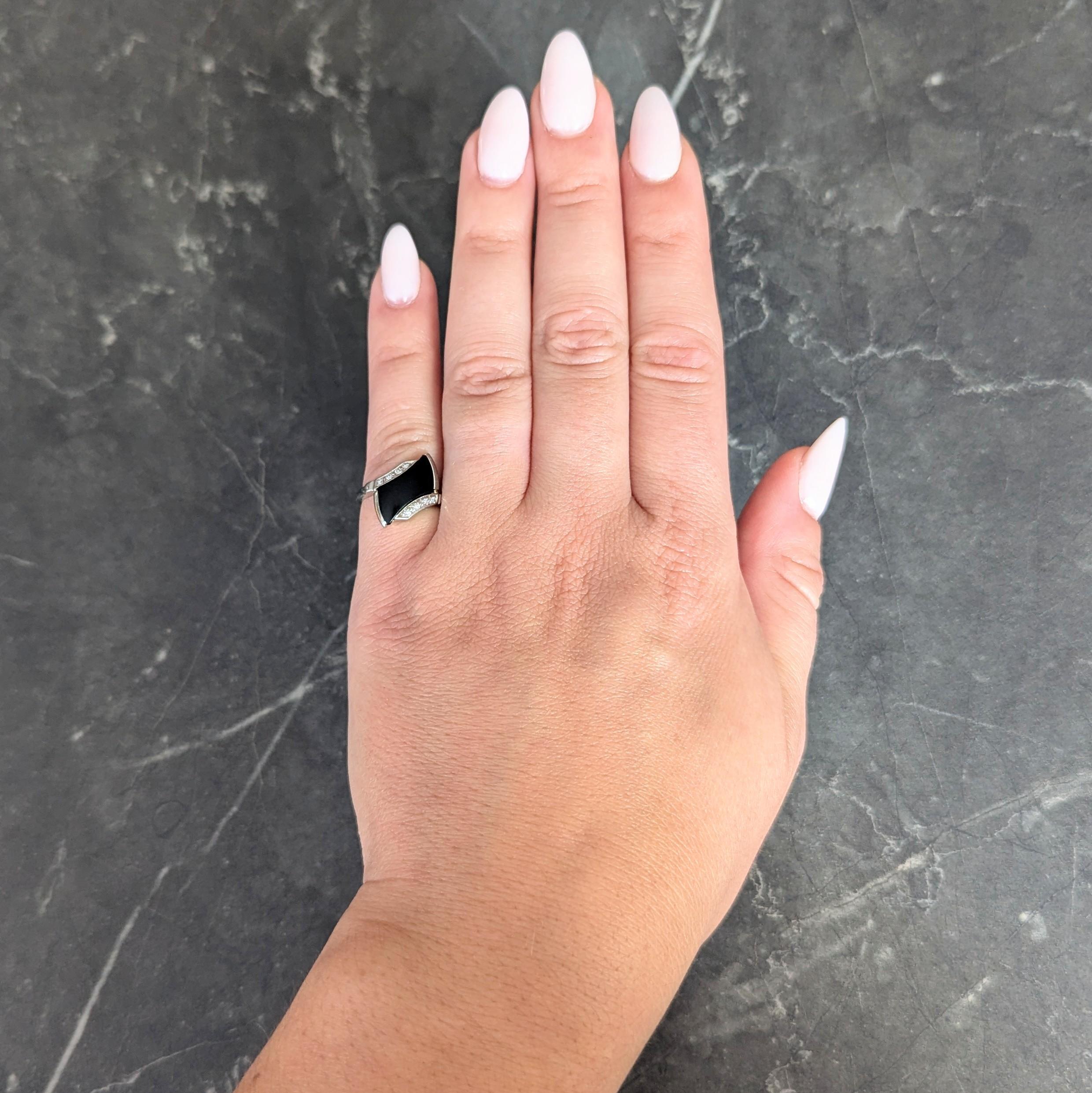 Designed as a bypass style ring centering a concave rectangular onyx tablet
Opaque matte black and measuring 12.0 x 7.0 mm - bar set at an angle
Flanked by tapered shoulders bead set with single cut diamonds 
Weighing approximately 0.08 carat total