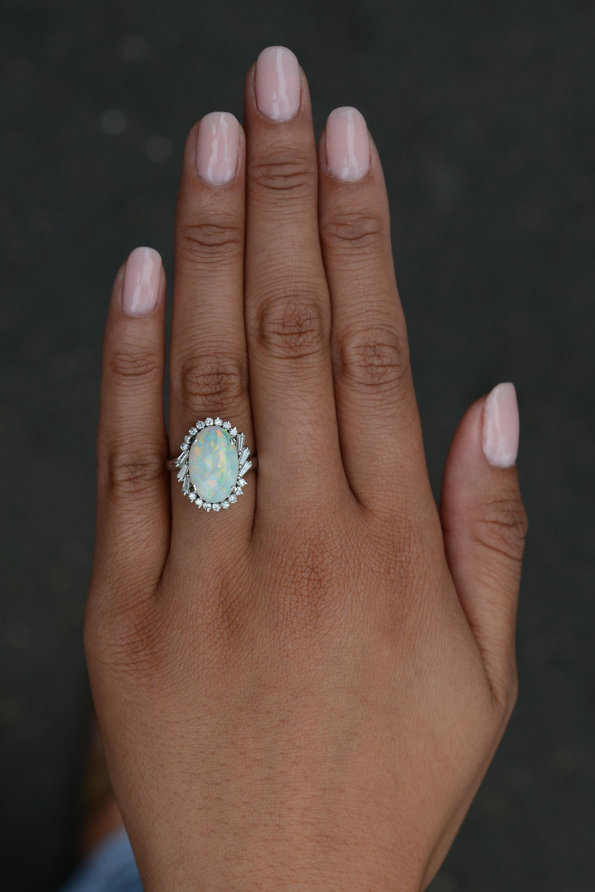 A stunning choice for any vintage jewelry collection. This estate cocktail ring features a striking 2.64 carat cabochon opal presenting a brilliant play of color. Its mid-century design offers a halo of 22 diamonds for exquisite sparkle, made unique