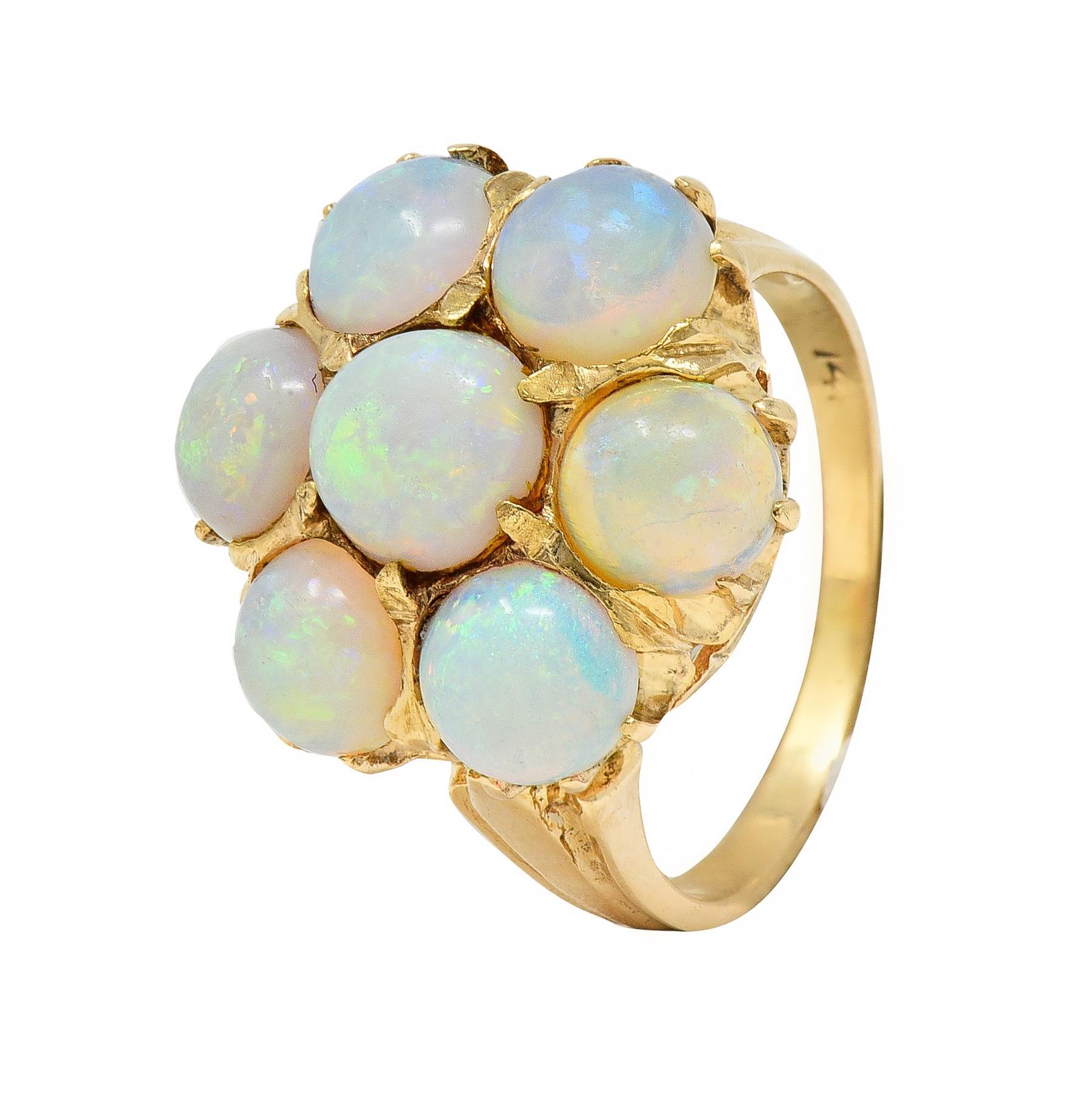 Centering a 6.0 mm round opal cabochon with a floral motif cluster surround
Comprised of additional 5.0 mm round opal cabochons - well-matched
Translucent white in body color with spectral play-of-color
All prong set in a pierced gallery
Flanked by
