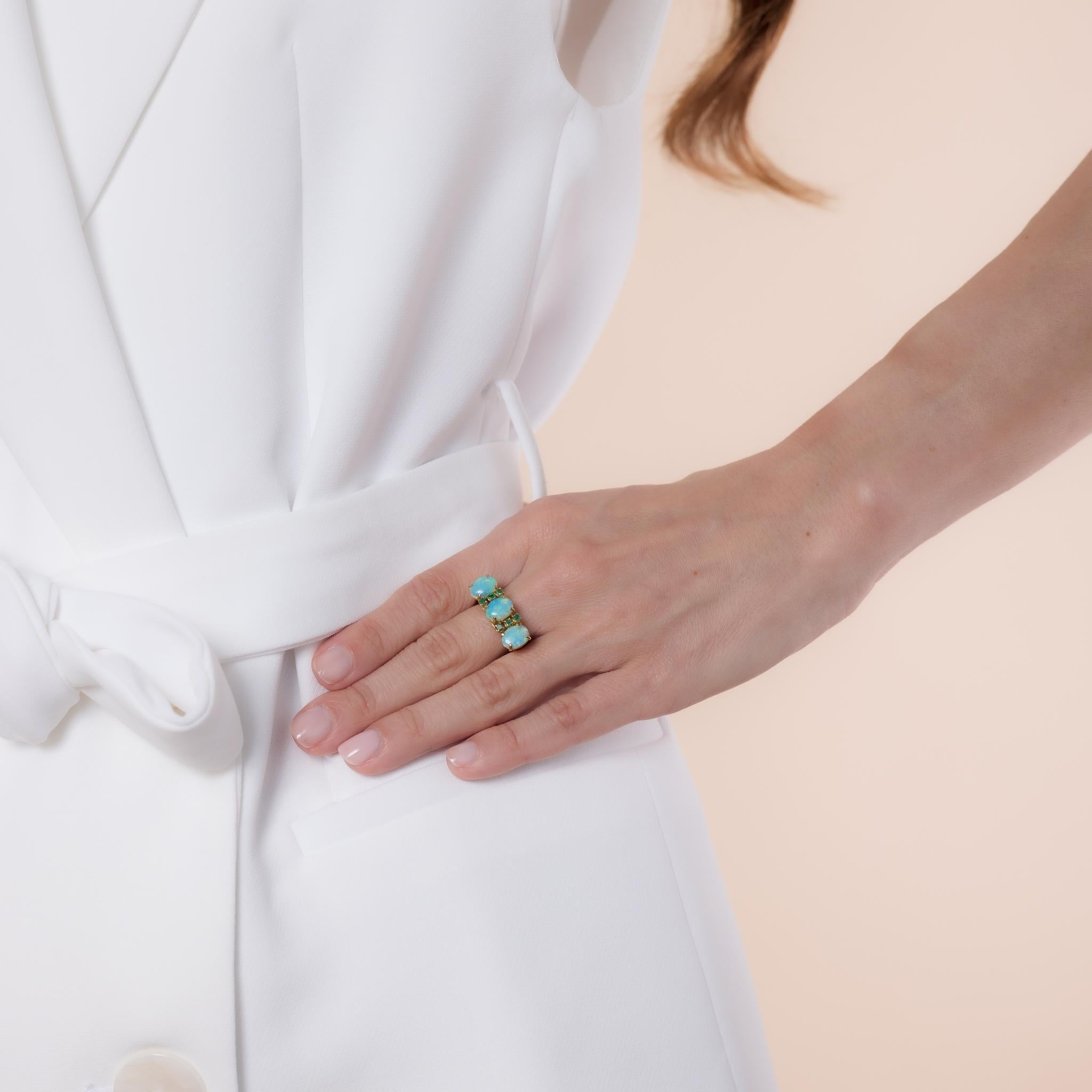 This Mid Century 14k yellow gold cocktail ring showcases three cabochon cut opals, approximately 8mm x 5.87mm, accented by six round brilliant cut emeralds totaling .20 carats. A vibrant design from the 1960s, hallmarked with a purity mark.

Center
