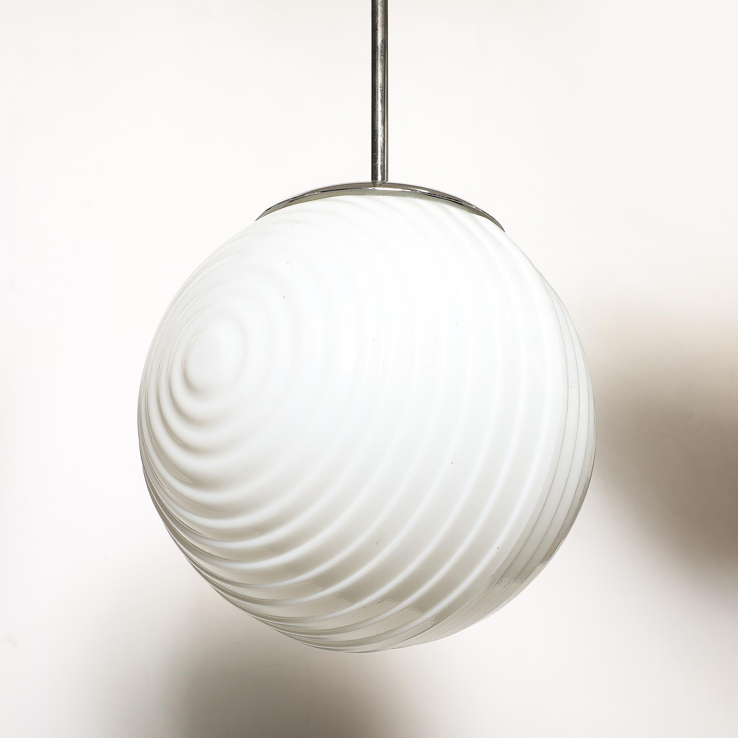 Questo straordinario lampadario a sospensione del Mid-Century Modernist è un notevole esempio di design ceco del dopoguerra, che combina funzionalità elegante e artigianato artistico. Il paralume in vetro opalescente vanta una superficie dalla