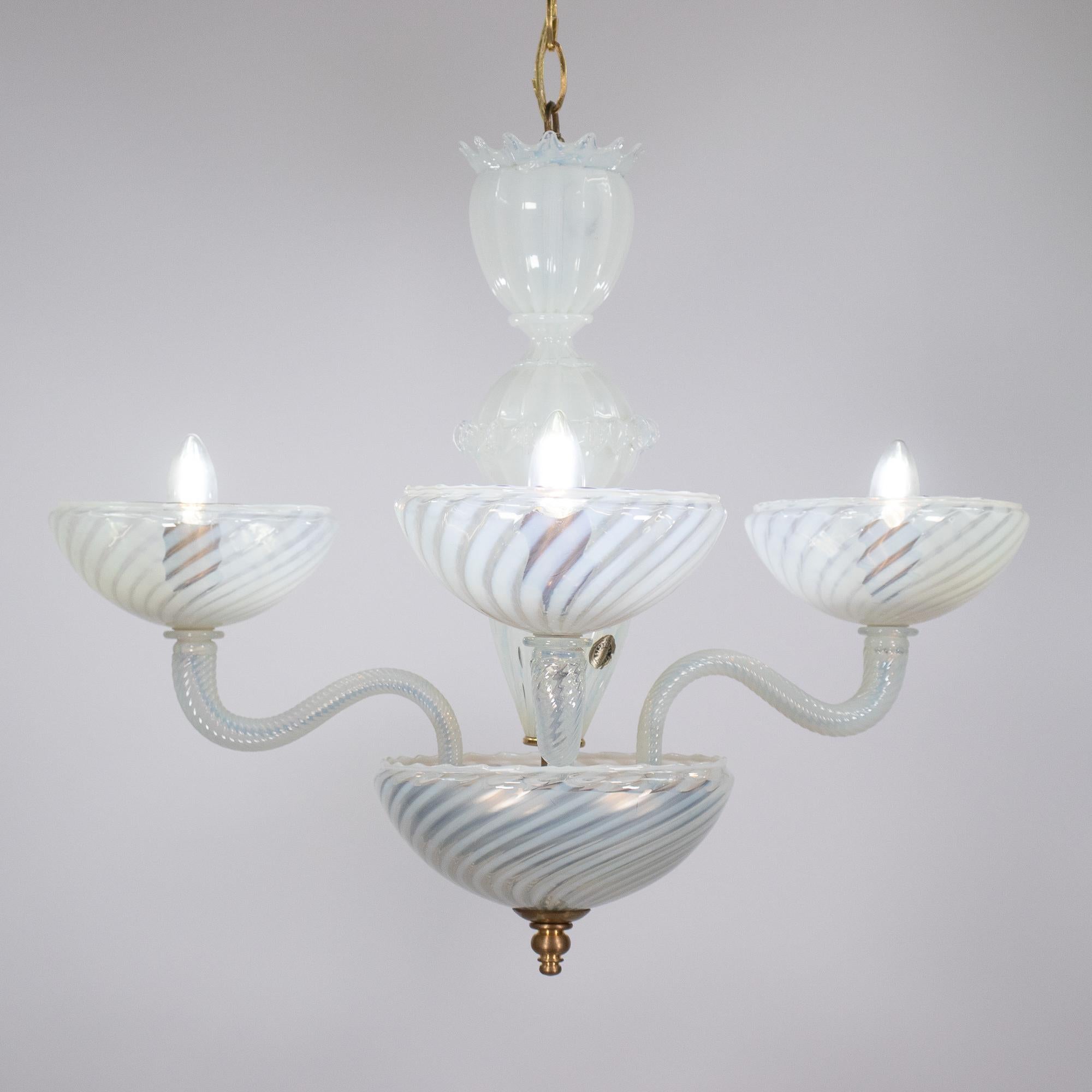 Questo lampadario di Murano soffiato a mano presenta una raffinata tavolozza opalina di Filigrana, la cui traslucenza lattiginosa è caratterizzata da morbide strisce a spirale che si illuminano con calore. L'unione del vetro opalino e della