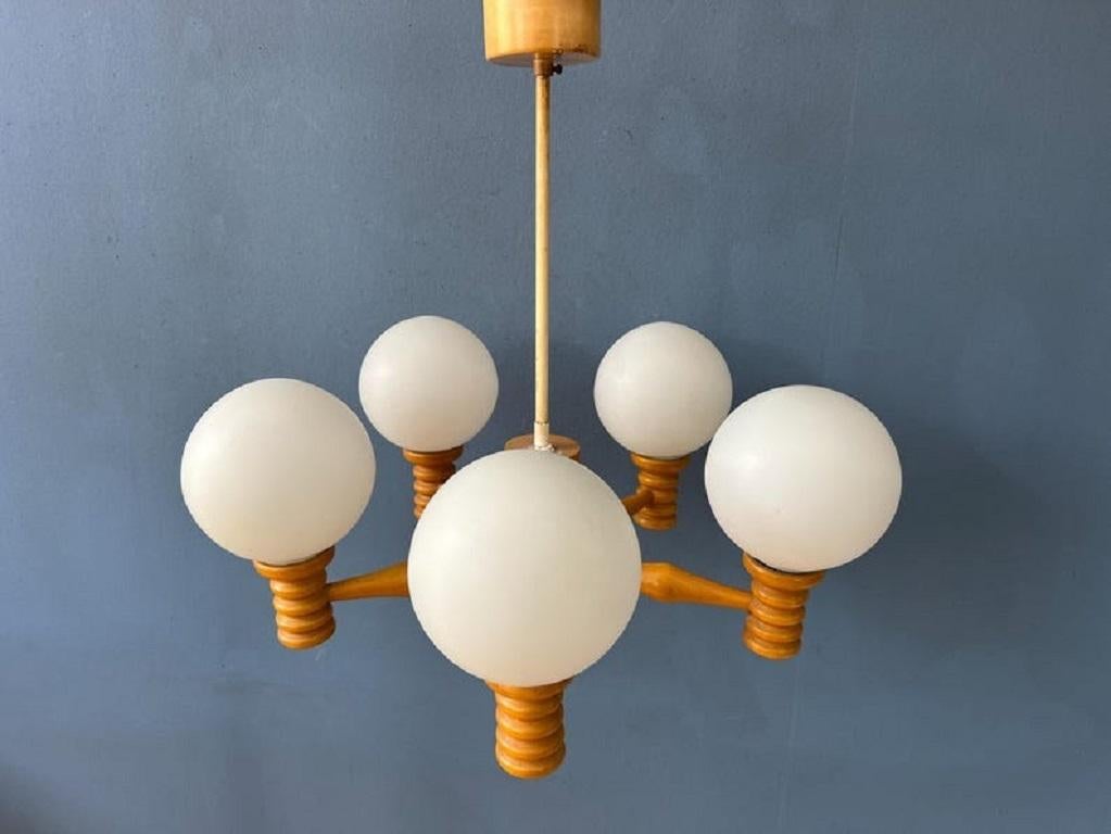 Mid opaline glass chandelier with five glass shades and a wooden frame. The lamp requires five E14 lightbulbs.

Additional information: 
Materials: Glass, metal
Period: 1970s
Dimensions: ø Chandelier: 59 cm
Height frame: 25 cm
Condition: Good. The