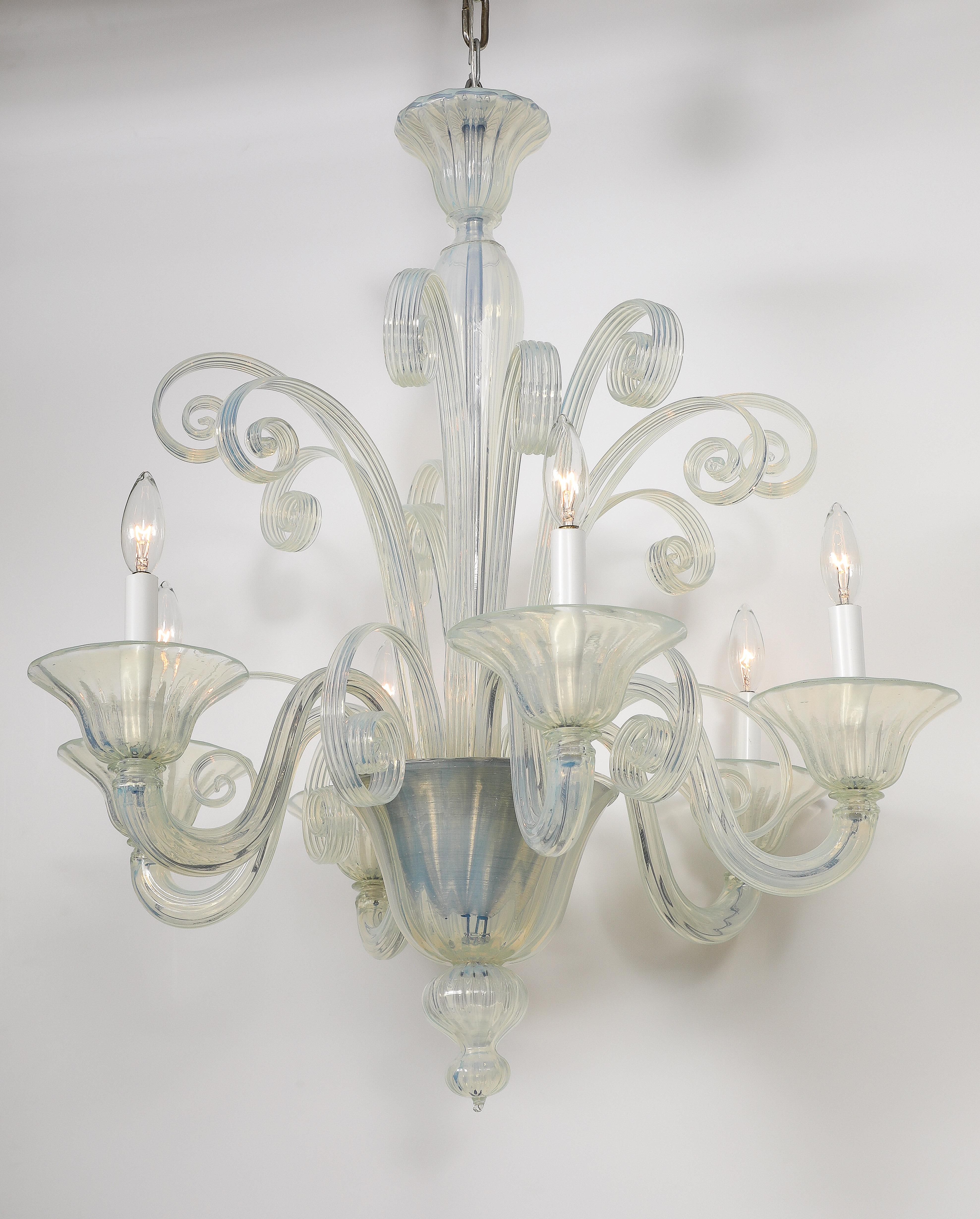 Stunning Mid Century opaline Murano glass chandelier with 6 light sources and fanciful curled glass stylized ribbons. Rewired for use in 110v locations. Uses candelabra type bulbs.