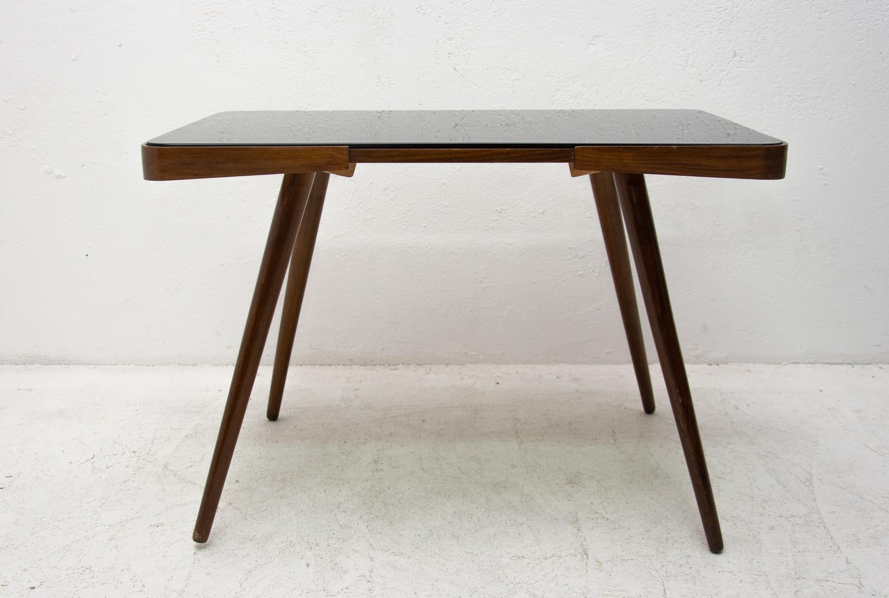 Midcentury opaxite glass coffee table from the 1960s. Associated with the world-renowned exhibition EXPO 58 in Brussels. It was produced by Ceský nábytek company. It features a beechwood structure and a black glass tabletop. In very good Vintage