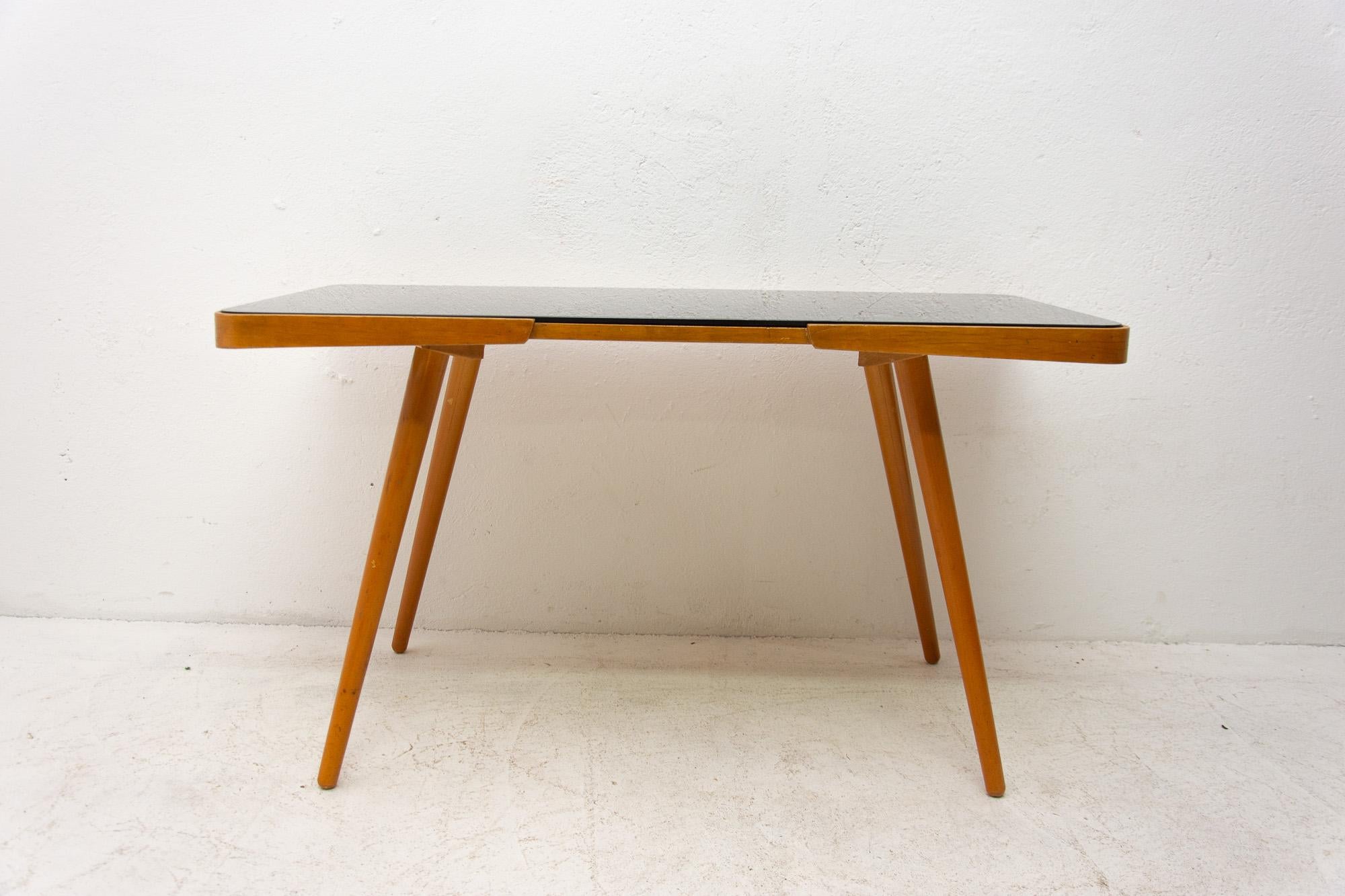 Midcentury opaxite glass coffee table from the 1960s. Associated with the world-renowned exhibition EXPO 58 in Brussels. It was produced by “Interior Praha”. It features a beechwood structure and a black glass tabletop. In very good vintage