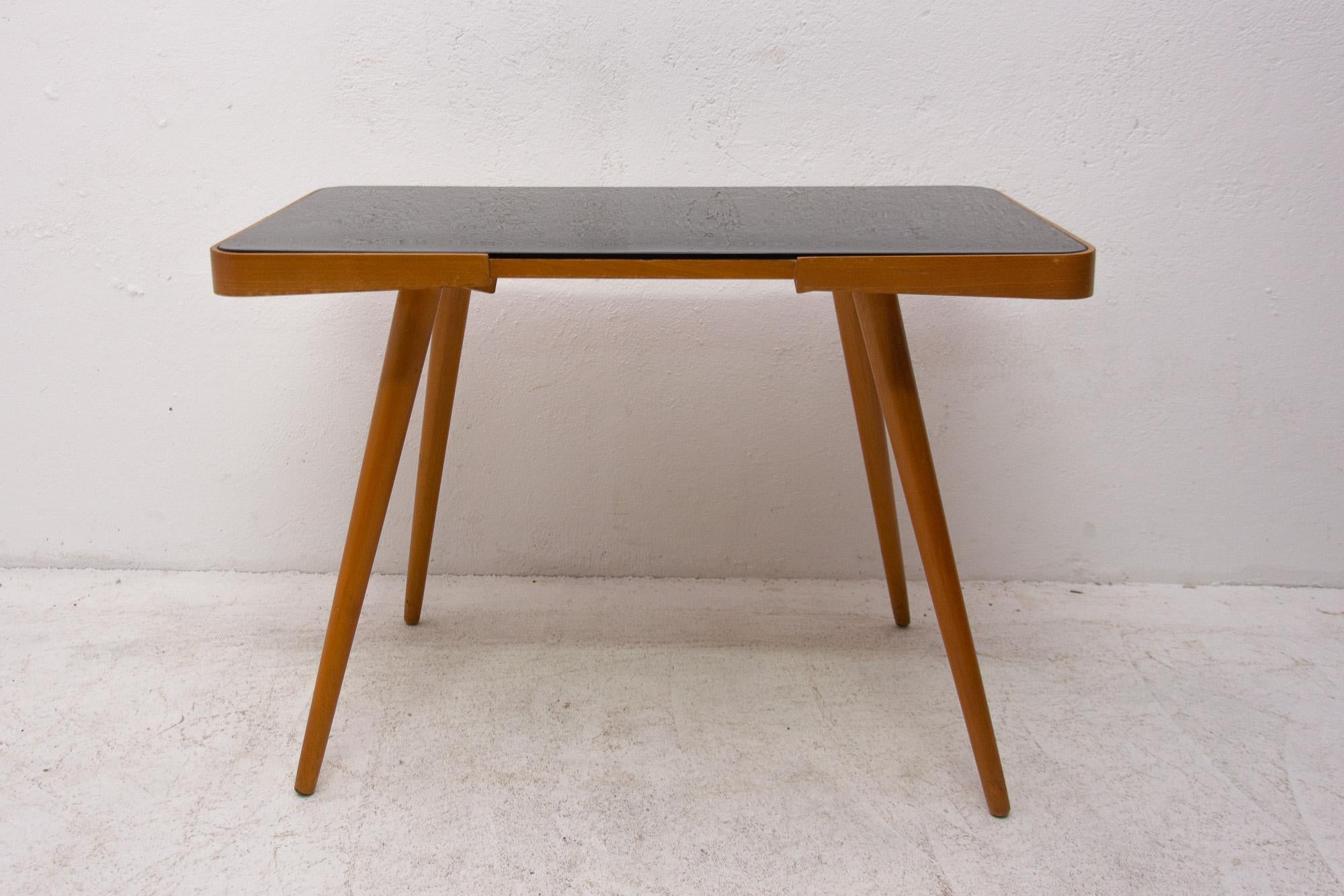 Midcentury opaxite glass coffee table from the 1960s. Associated with the world-renowned exhibition EXPO 58 in Brussels. It was produced by “Interior Praha”. It features a beechwood structure and a black glass tabletop. In very good Vintage