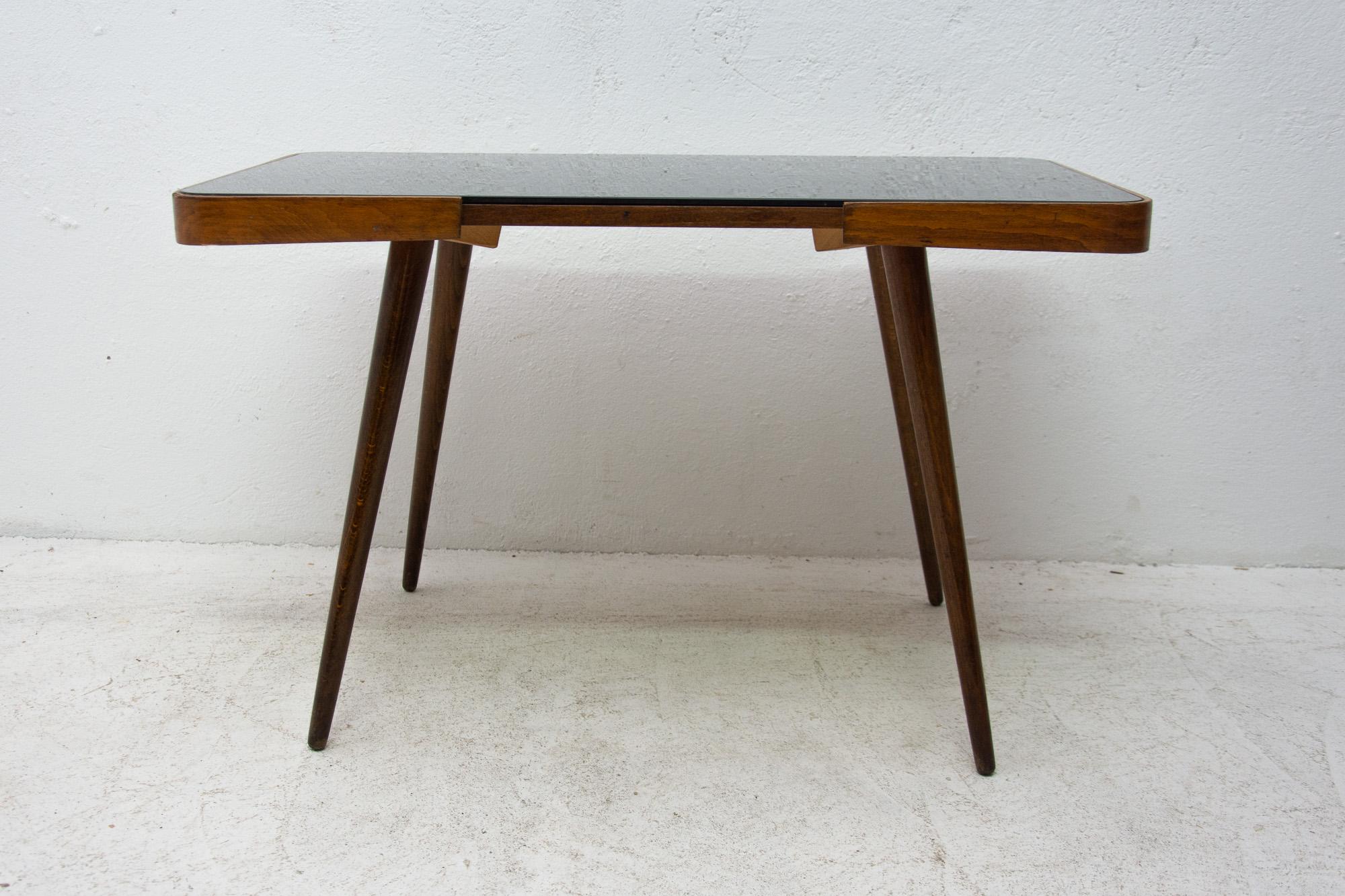 Midcentury opaxite glass coffee table from the 1960s. Associated with the world-renowned exhibition EXPO 58 in Brussels. It was produced by “Interior Praha”. It features a beechwood structure and a black glass tabletop. In very good vintage