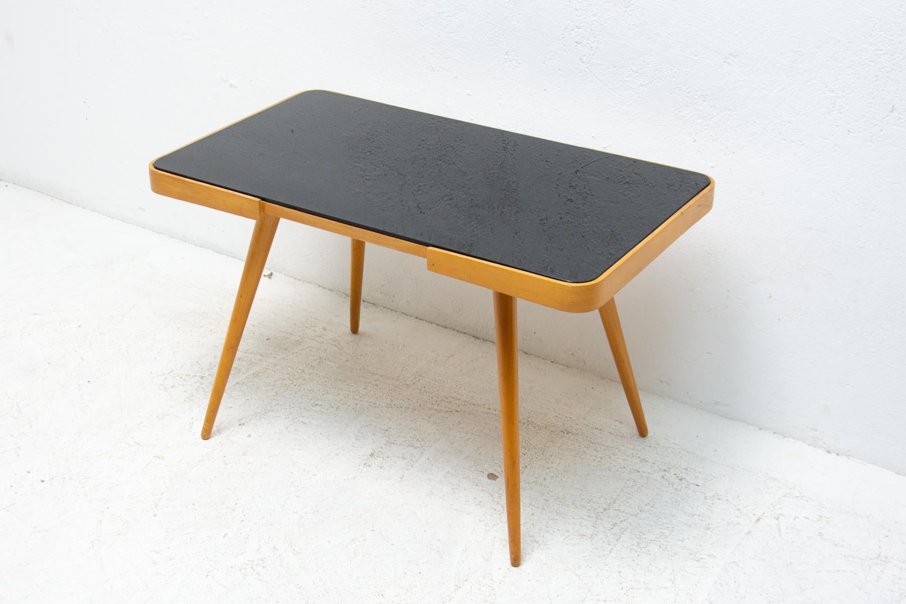 Mid century opaxite glass coffee table from the 1960s. Associated with the world-renowned exhibition EXPO 58 in Brussels. It was produced by “Interiér Praha”. It features a beechwood structure and a black glass tabletop. In very good Vintage