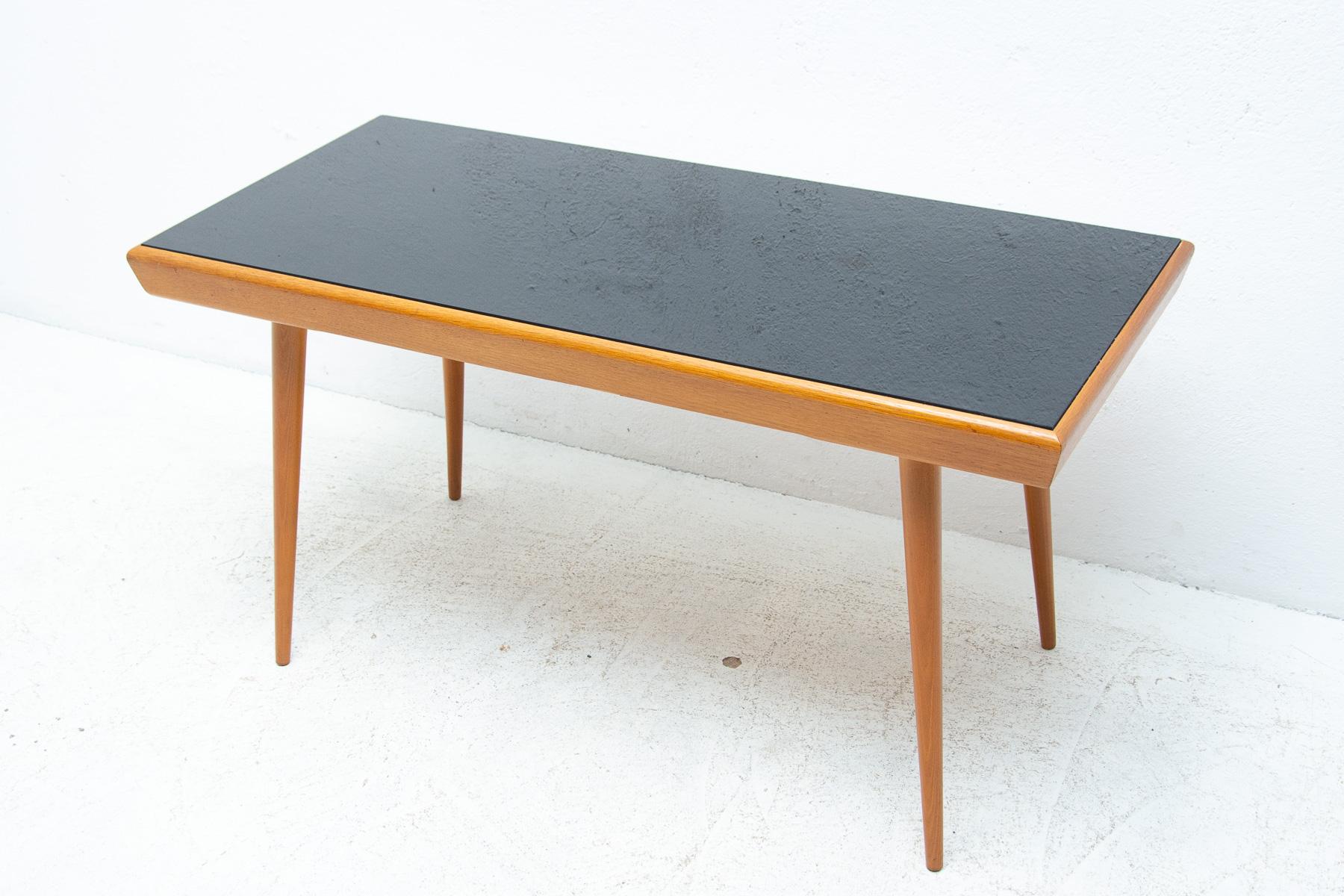 Mid century opaxite glass coffee table from the 1960´s. Associated with the world-renowned exhibition EXPO 58 in Brussels. It was produced by “Interiér Praha”. It features a beechwood construction and a black glass tabletop. In good Vintage