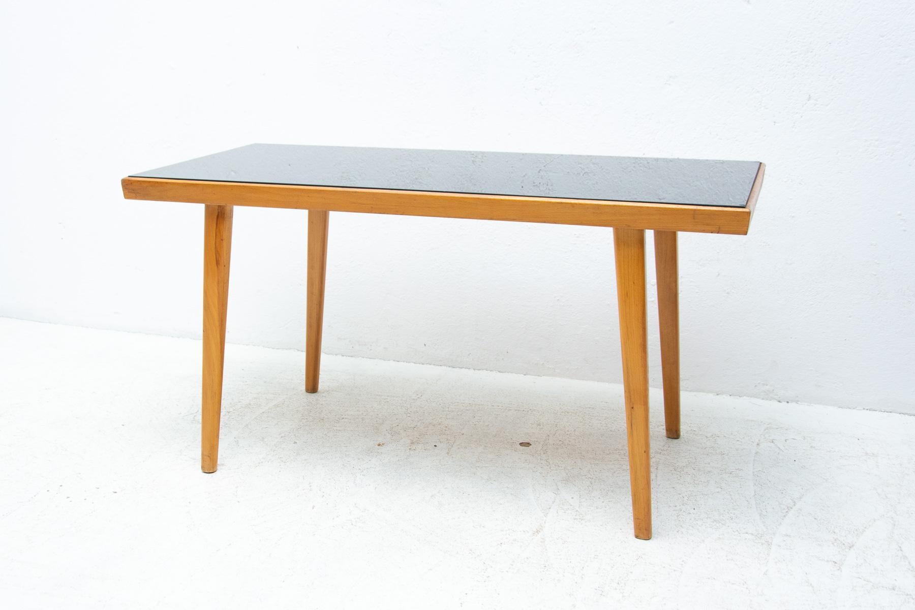 Mid century opaxite glass coffee table from the 1960´s. Associated with the world-renowned exhibition EXPO 58 in Brussels. It was produced by “Interiér Praha”. It features a beechwood construction and black glass tabletop. In good Vintage condition,