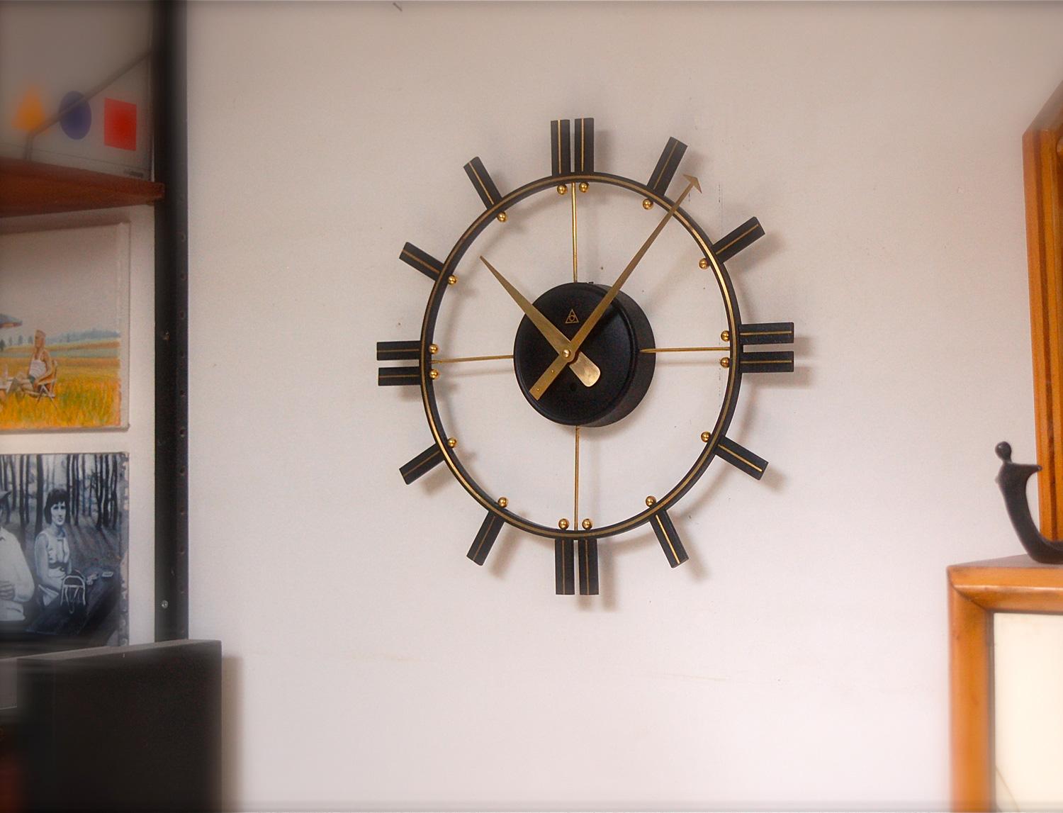 Large, midcentury, modernist, black and gold open face wall clock made from black lacquered metal with brass and gold coloured metal detailing. This clock was serviced by an horologist who put in a battery operated mechanism.