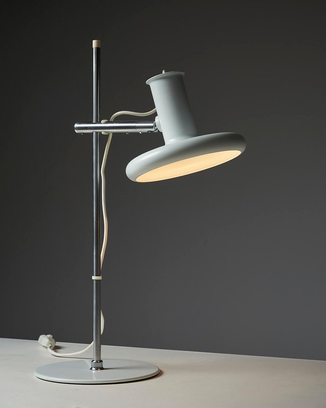 The Optima Lamp Series, designed by Hans Due for FOG&MØRUP, is a collection of futuristic-looking lamps that have become a design classic. This table lamp features a tin white base with a chromed stem, topped by the adjustable lampshade that is
