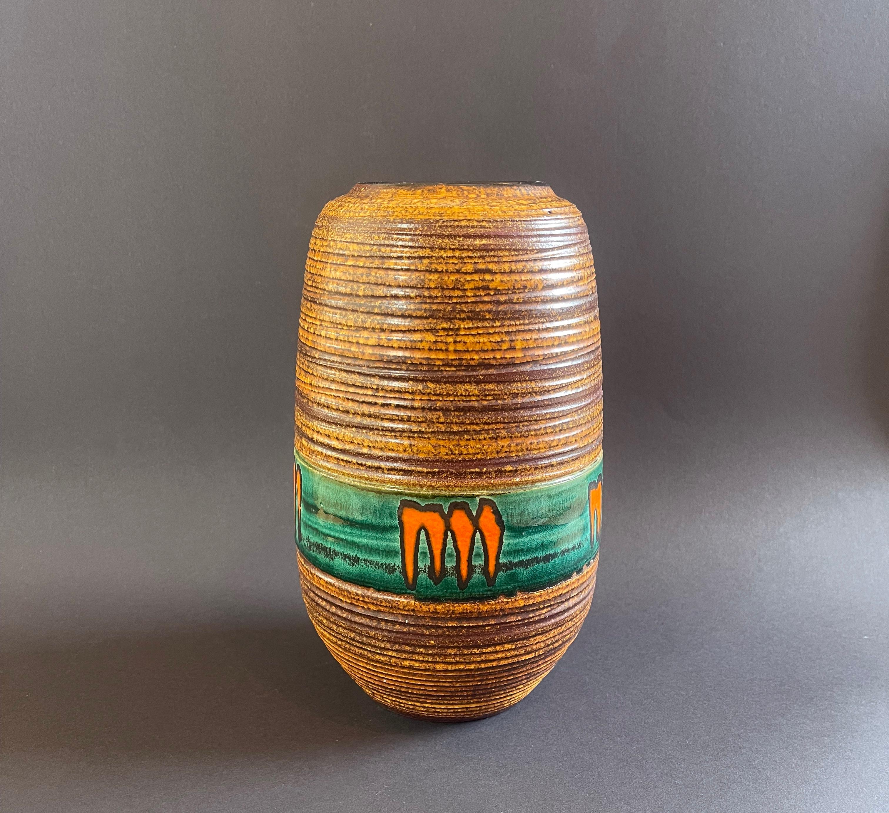 Funky original mid-century ceramic vase in the time of ''Fat Lava'' pottery.
Here in a typical German orange to brown speckled and stripe textured glaze, featuring the absolutely fun and bright orange
carrot or ''monster'' claw decoration on a dark
