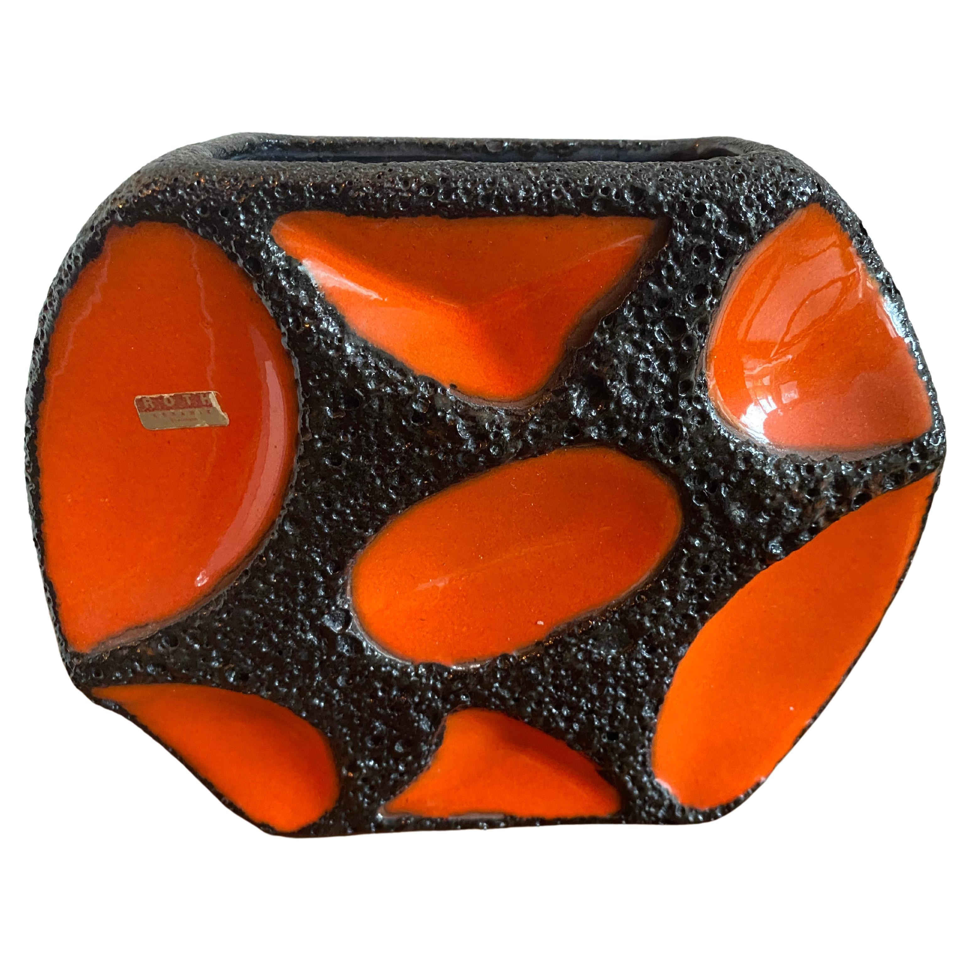 Un vaso Roth Keramik, arancione con contorno di lava nera. Questi vasi sono molto ricercati.
Adesivo/etichetta originale presente.

