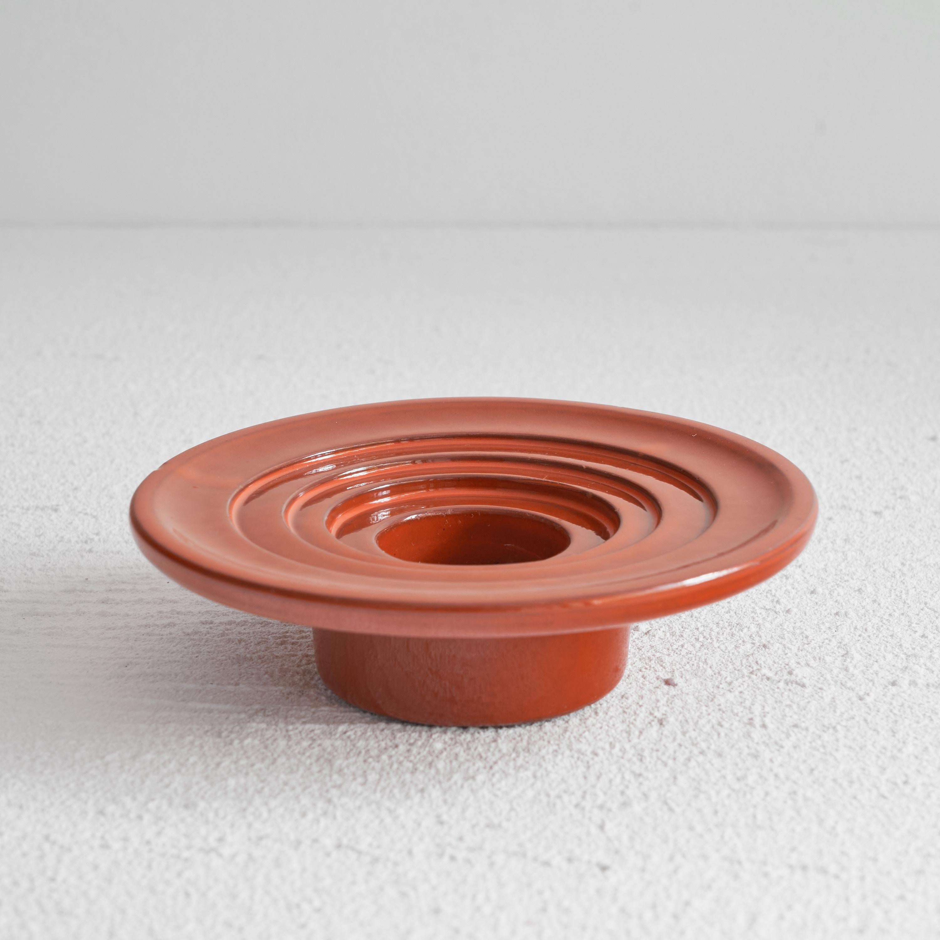 Orange glazed ceramic candle holder or decorative bowl. Mid 20th century. 

Eye catching orange glazed ceramic candle holder with a very distinct style. A studio pottery piece which was hand made somewhere in the middle of the last century. In