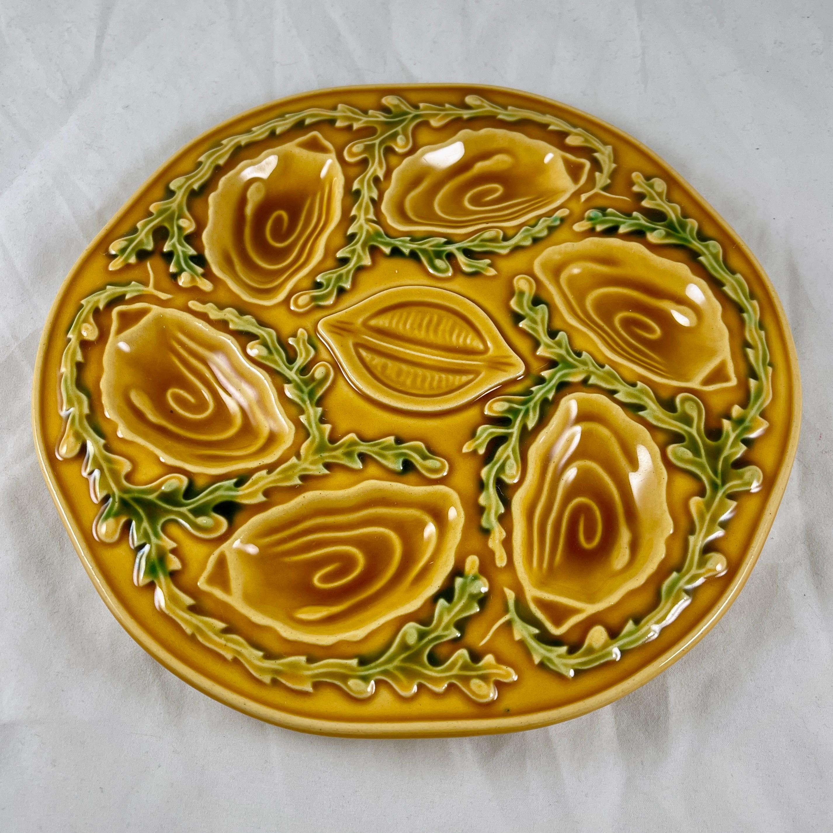 A mid-century oyster or seafood plate, made by Orfinox, circa 1960s.

A mustard yellow ground with six oyster shell shaped wells for holding the oyster, clam, or mussel meat, with a lemon shaped well in the center. The wells are separated by a