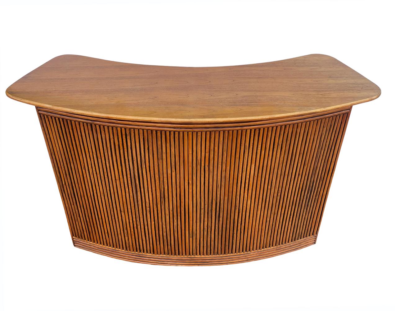 A lovely vintage dry bar circa 1960's. It features bamboo clad construction in a curved form with solid wood top. The rear interior has two shelves with tons of storage.