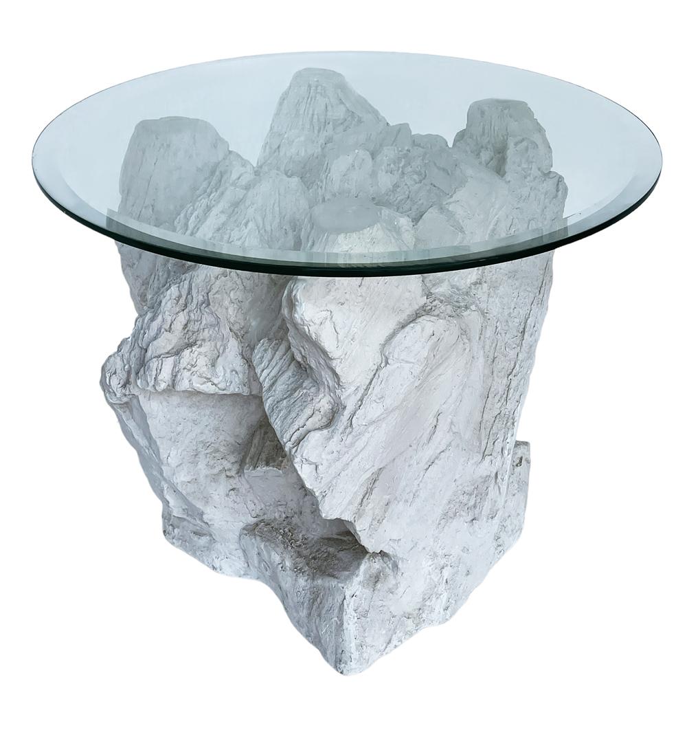 A sculptural faux rock formation table made by Sirmos in the 1970s. It features a plaster molded rock formation base with a clear glass top. Very good ready to use condition. 
   