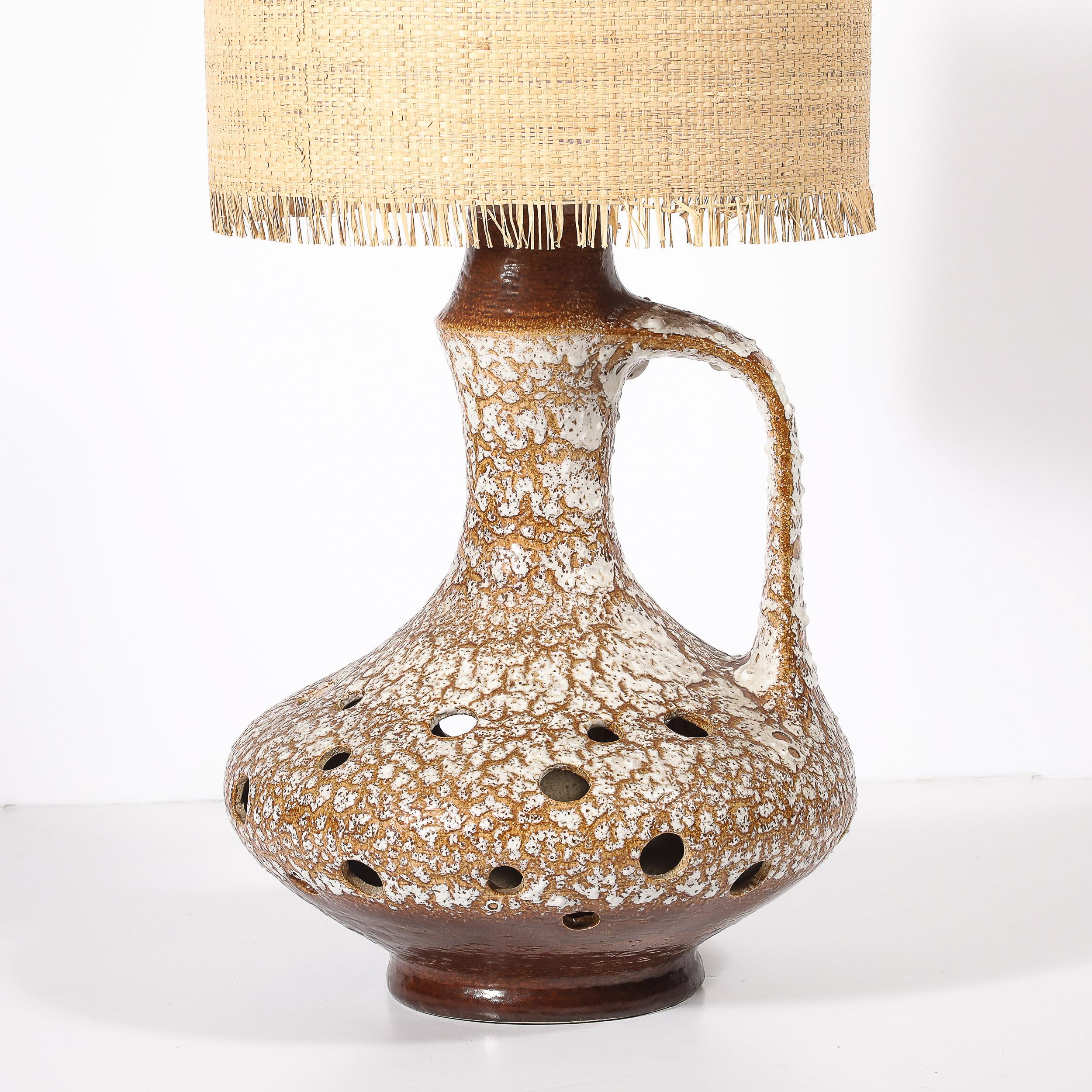 This stunning Mid-Century Modernist ceramic table lamp, crafted in France circa 1950, features an organic, pitcher-like form that embodies the era’s embrace of sculptural and naturalist design. The lamp seamlessly blends functionality with artistry,