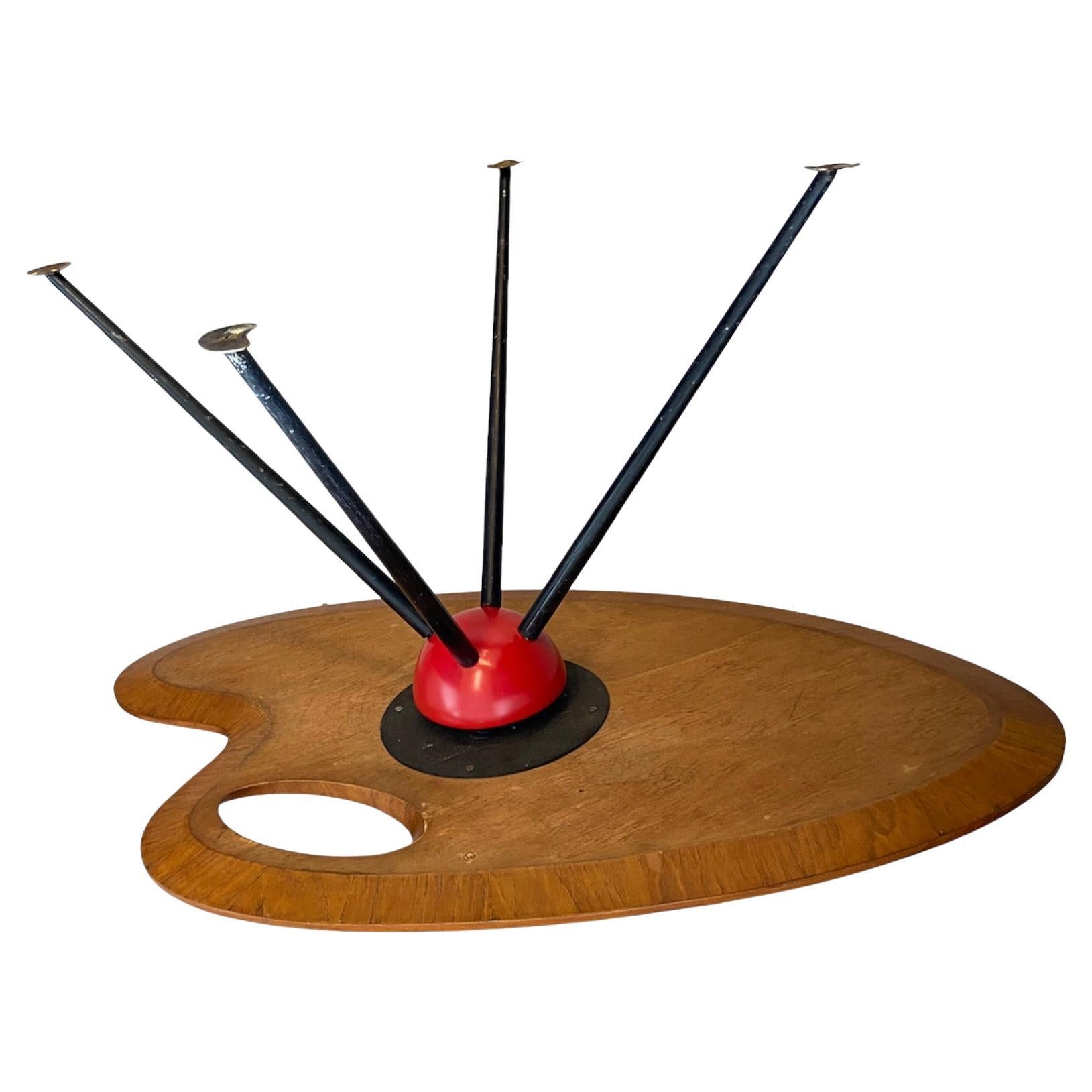 a beautifully shaped wooden coffee or side table on black painted metal legs ending on hammered brass feet. The red half sphere linking the top to the legs is very unusual and avant - garde for the period.