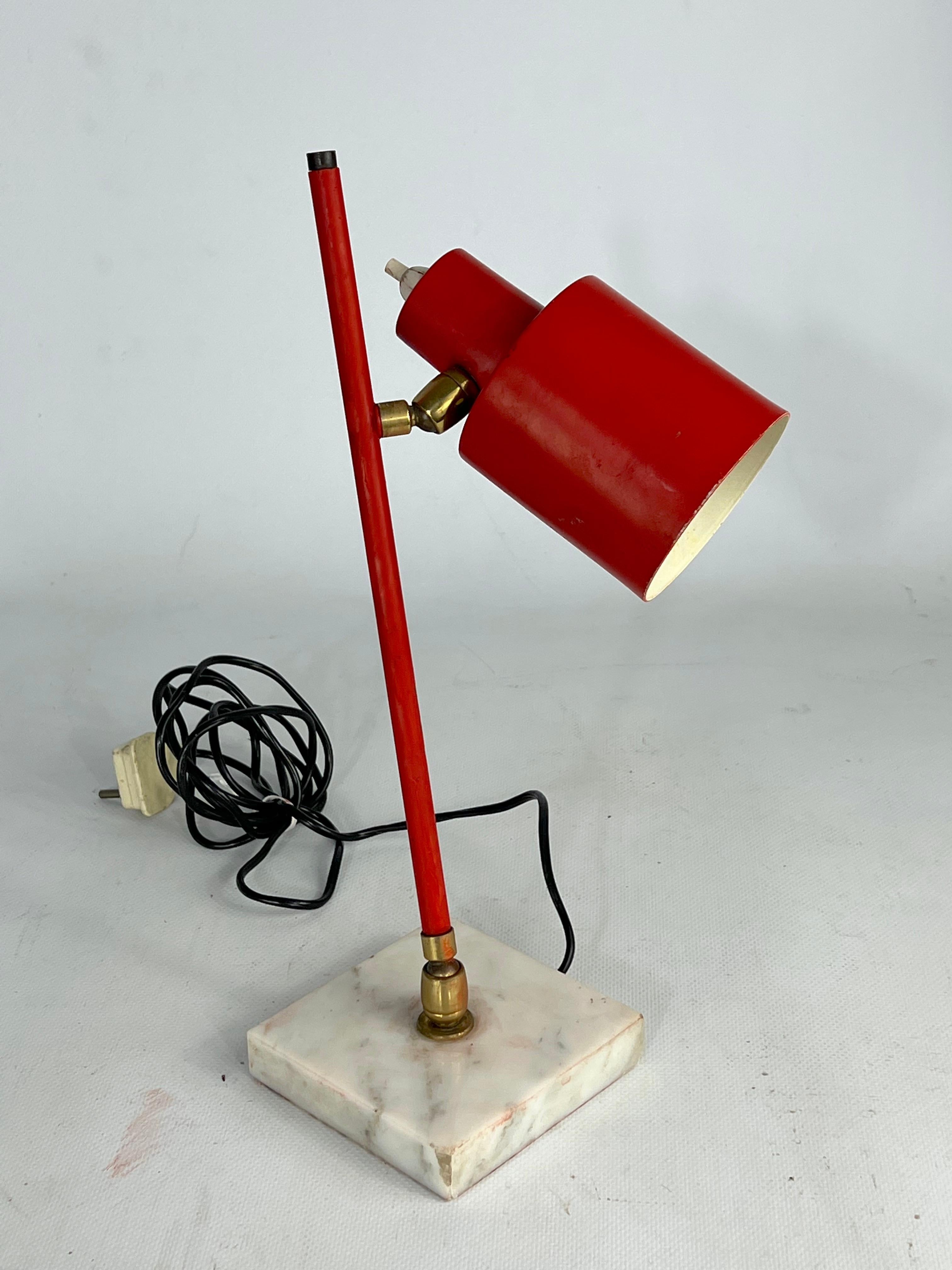 Vintage unaltered condition with evident trace of age and use for this red lacquered brass and marble table lamp by Stilux Milano and produced in Italy during the 50s. It mounts two joints, one on the cone and one on the base, that let it be