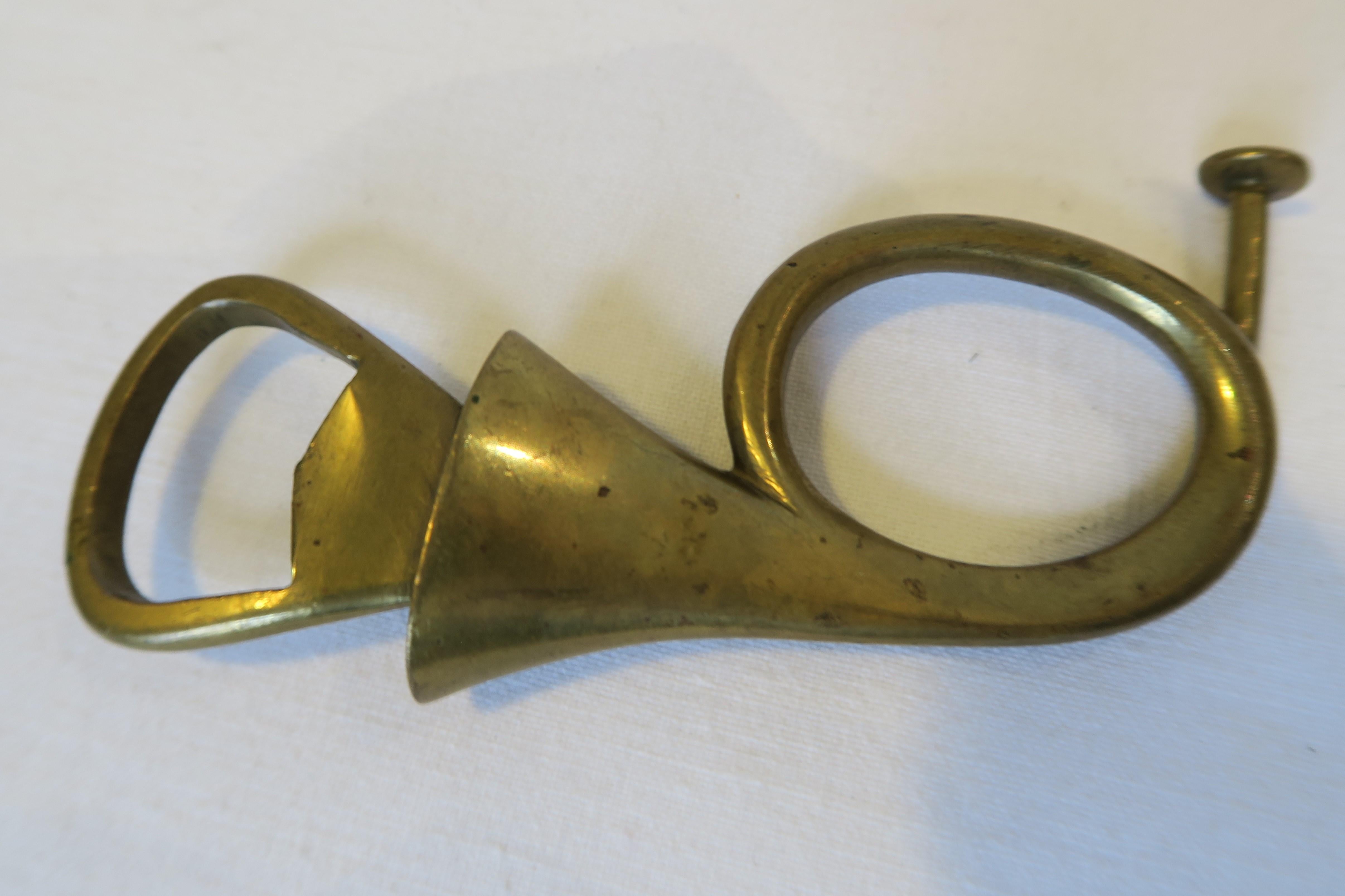 For sale is a beautiful bottle opener in the shape of a post horn. Both were crafted from brass and designed by the renowned workshops of Carl Auböck in Austria. The item is stamped 