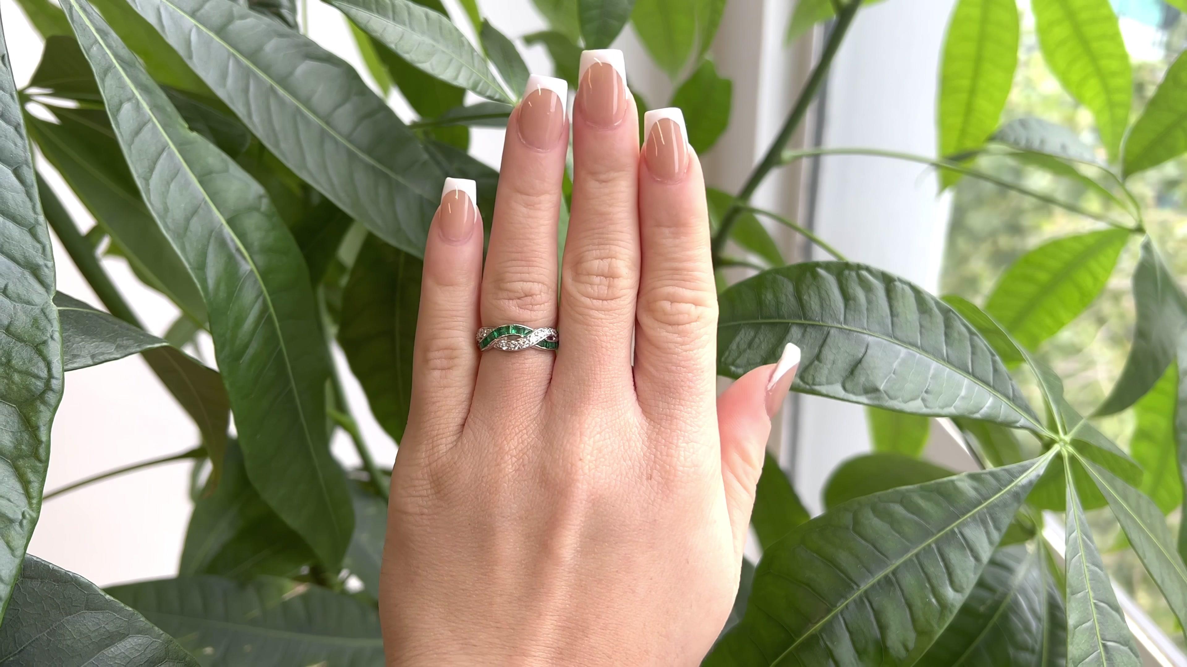 One Mid Century Oscar Heyman Diamond Emerald Platinum Twisted Ring. Featuring 12 round brilliant cut diamonds with a total weight of approximately 0.30 carat, graded D-E color, VVS clarity. Accented by 14 calibré cut emeralds with a total weight of
