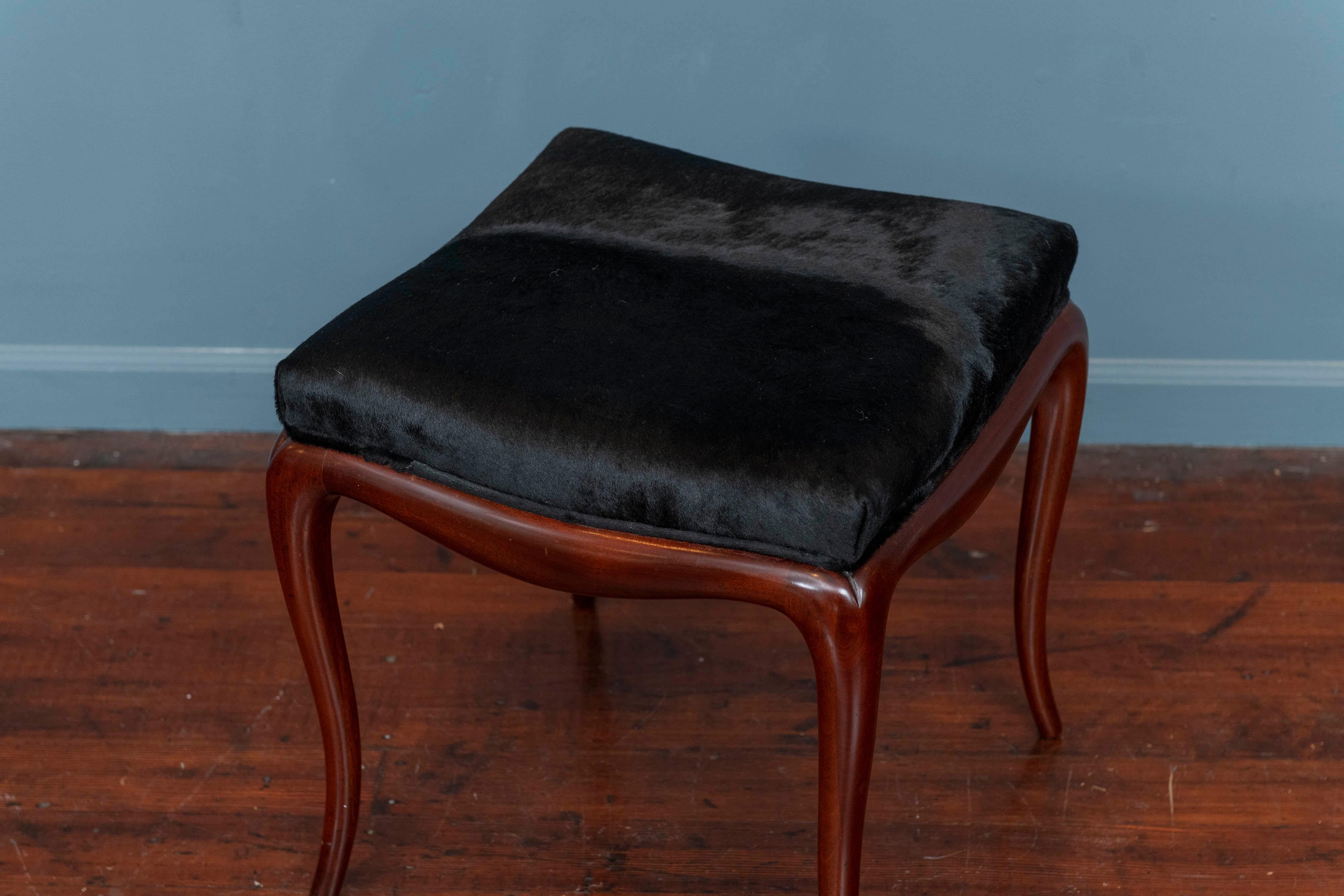 Mid-Century modern ottoman with cowhide. Sculpted mahogany frame with newly upholstered black cowhide, very sturdy and well made.