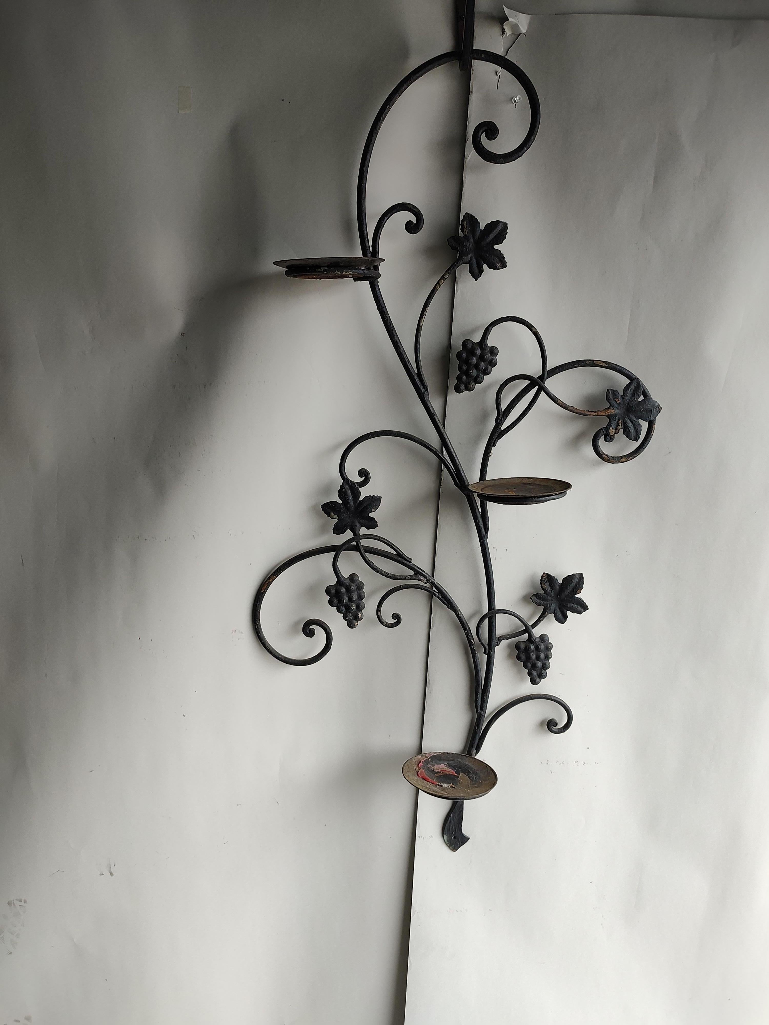 Fabulous decorative iron wall bracket for patio or outdoor use. Has three holders for candles plants or vases or any combo. Grape with leaf decorative casting with old black paint. In excellent vintage condition with lots of patina.