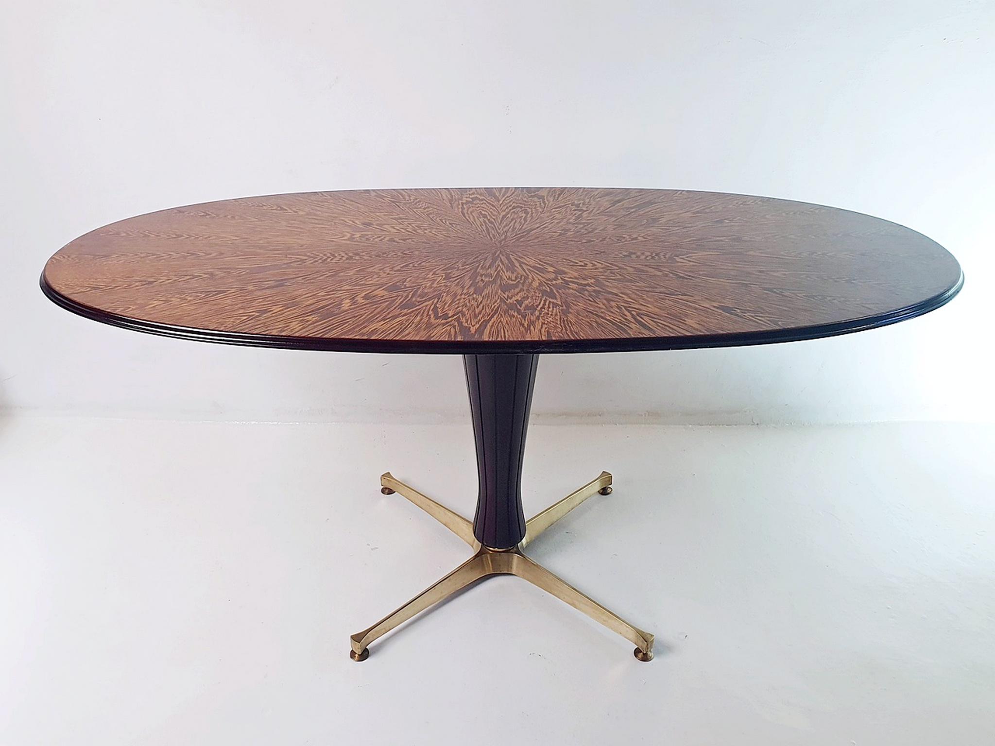 Midcentury oval dining table in mahogany. The tabletop rests on a center pillar in solid brass feet. The top which is unique in its composition has been restored and is in perfect condition. The table will sit between 6 persons comfortably and a