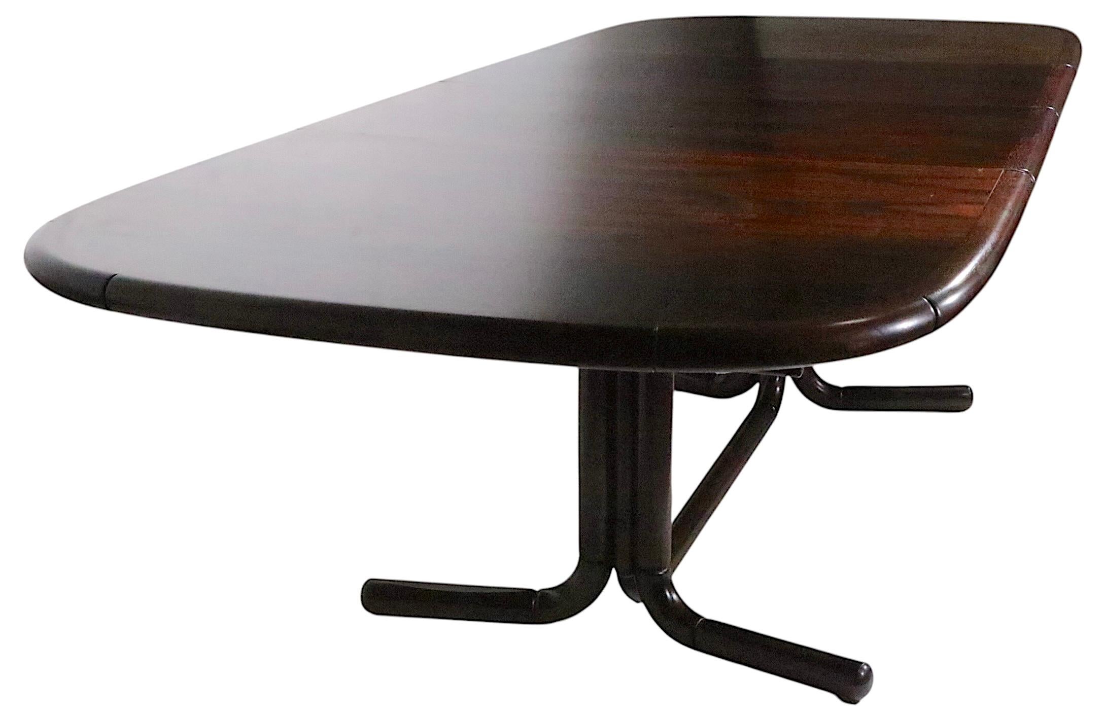 Palisandro sofisticado  Mesa de comedor Mid Century Modern de Boltinge, fabricada en Dinamarca,  circa 1960/70's. La mesa presenta un gran tablero ovalado que se abre para admitir dos hojas, montado sobre una inusual base en forma de caballete con