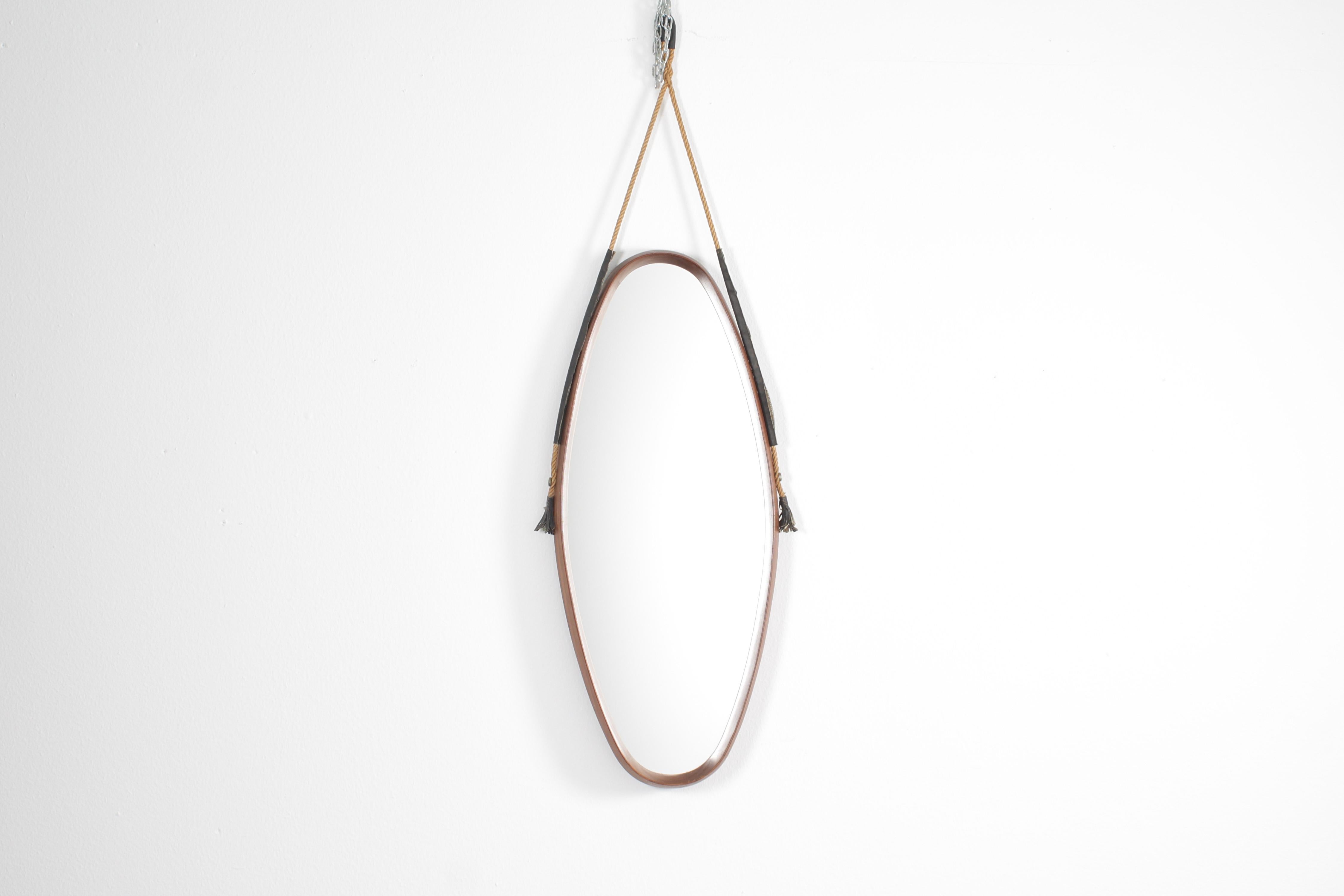 Specchio ovale verticale con cornice sporgente con fascia in teak curvato. È appeso a una corda con elementi in pelle. Produzione italiana degli anni '60.
Usura coerente con l'età e l'uso.