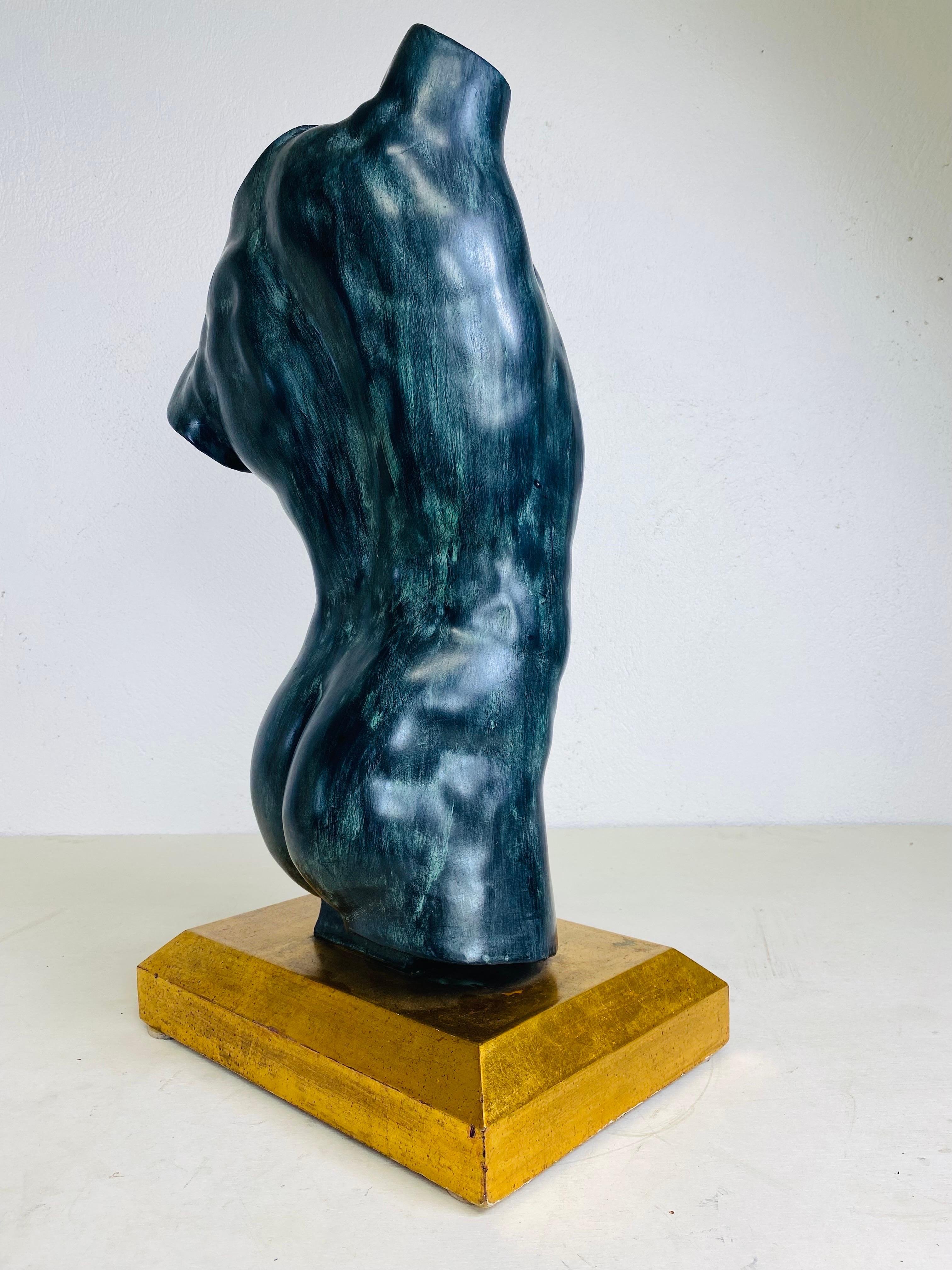 This is a mid century oversized male nude torso in plaster. This Italian plaster sculpture has a dark green patinated bronze finish to the surface. The sculpture rests on a gold gilded rectangular base. This large sculptor was made in Italy circa