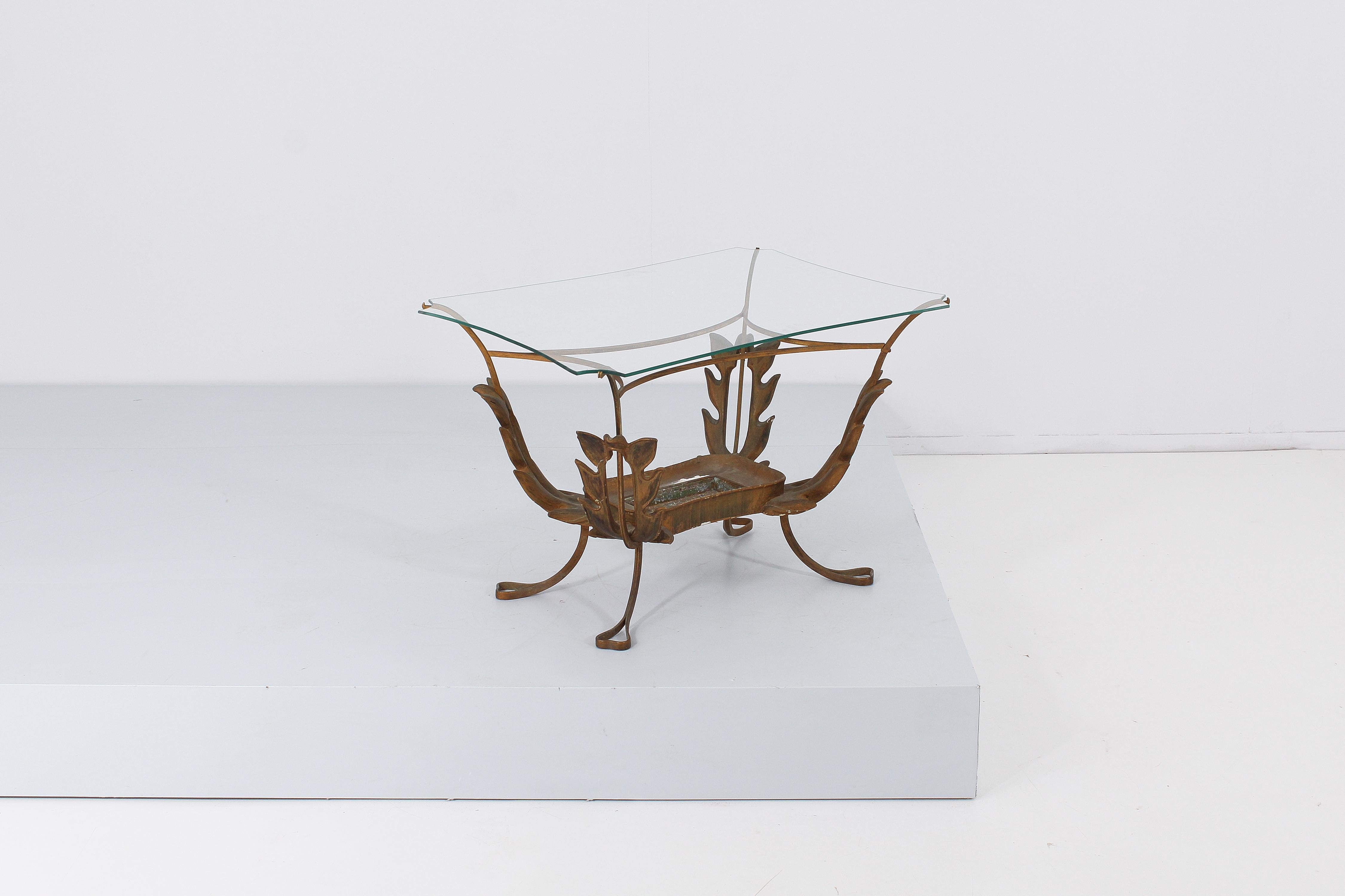 Delicious rectangular coffee table in curved brass, shaped glass top and decorative elements in the shape of large leaves in carved and lacquered wood. Under the glass top, a metal tray (worn as seen in the photo) can hold a plant, making the table