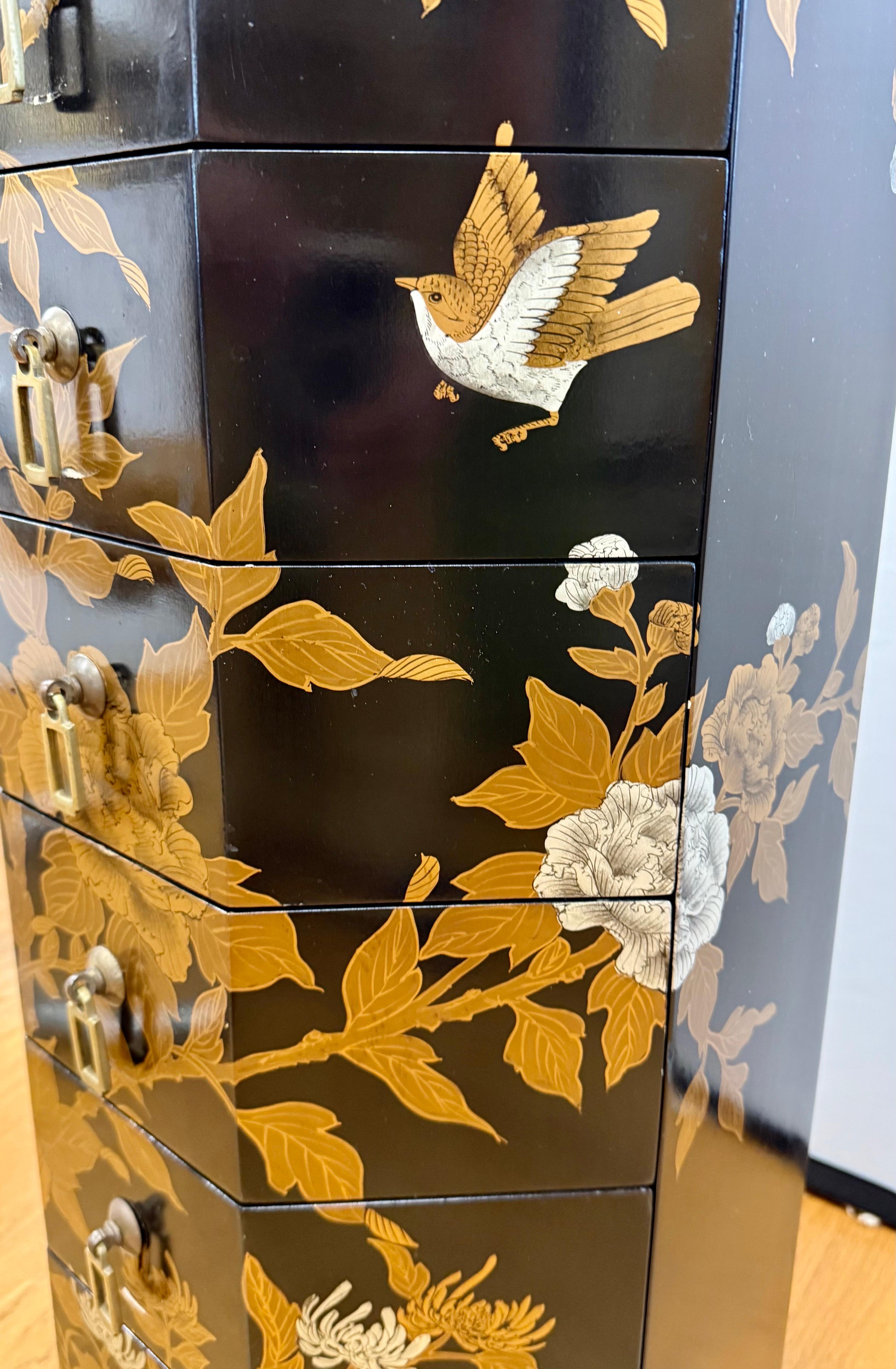 Lo splendido portagioie vintage in laccato nero Silhouette ha una forma ottagonale e mostra fiori di peonia e uccelli dipinti a mano in oro e argento.  Otto spaziosi cassetti si aprono grazie a tiranti in ottone scintillante e offrono un ampio