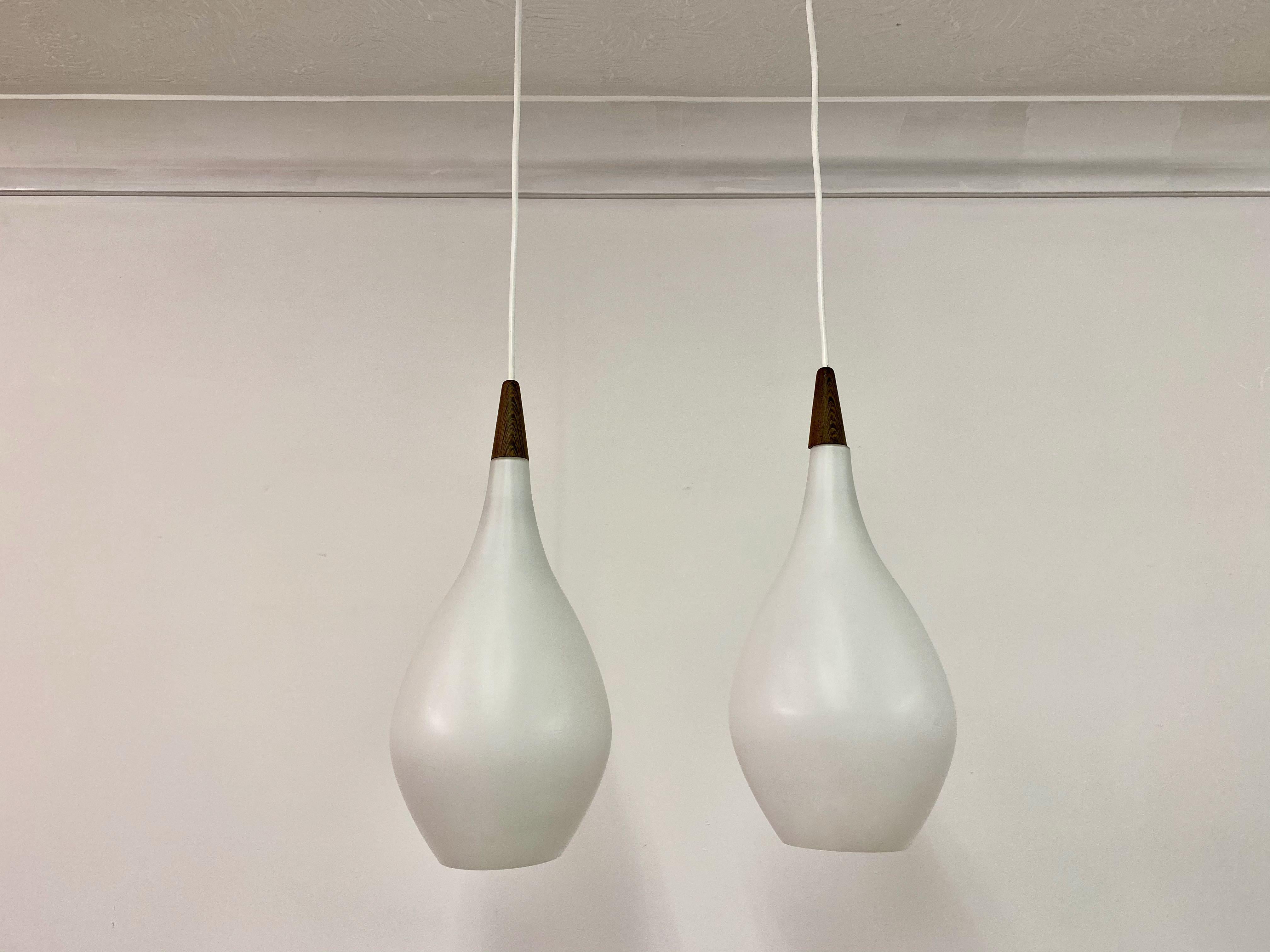 Pair of teardrop shaped pendants

Opaline glass

Wenge top

Probably by Holmegaard

New electrical components

Some small chips to bottom

Measurements do not include the cord

One lamp stamped made in Denmark to cork