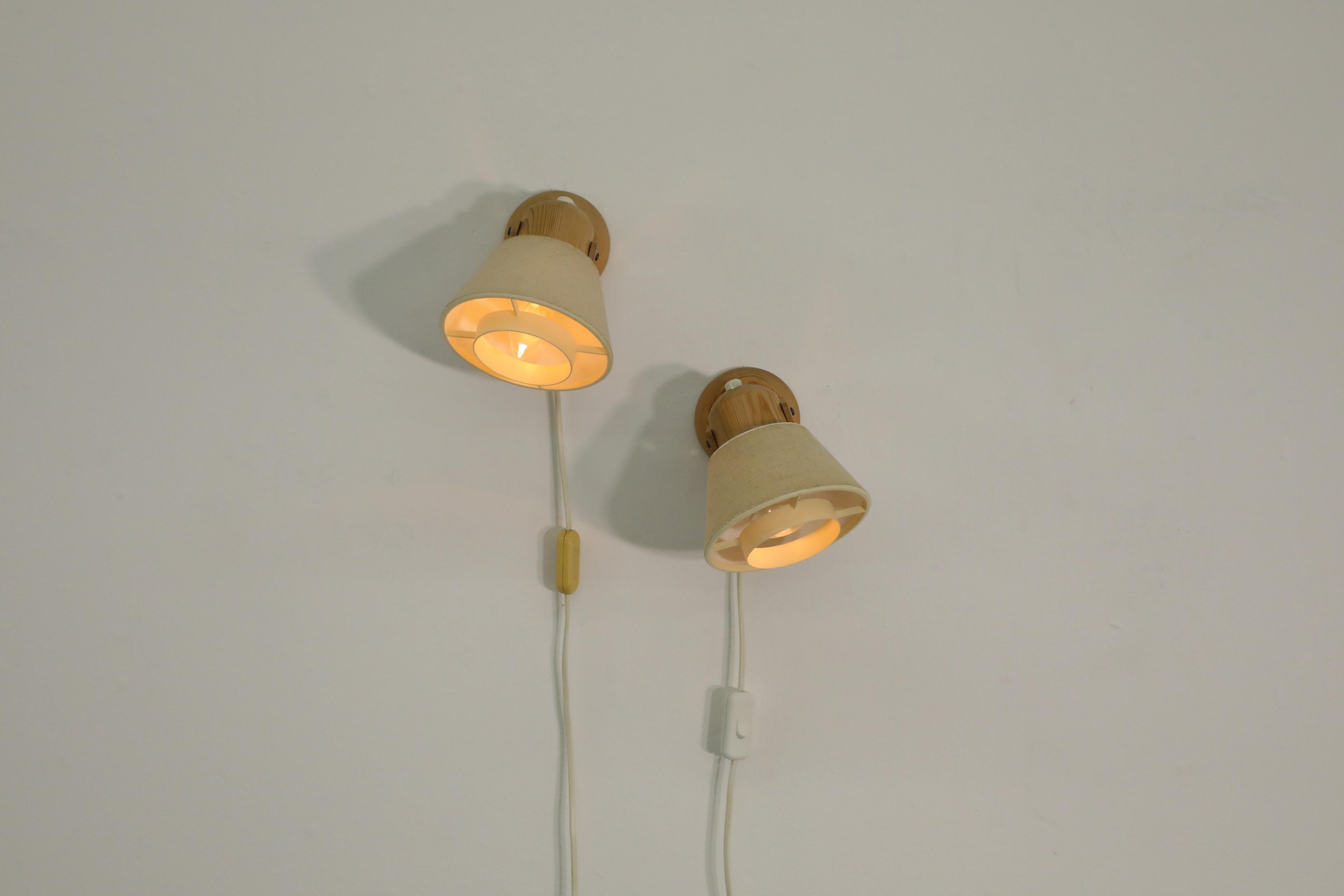 Pair of Mid-Century pine sconces with textured beige fabric shades by Swedish manufacturer AB Solbackens Svarveri, 1970s. Matching pair with spot sconces that can be coupled or styled separately for directional ambient lighting. In overall original