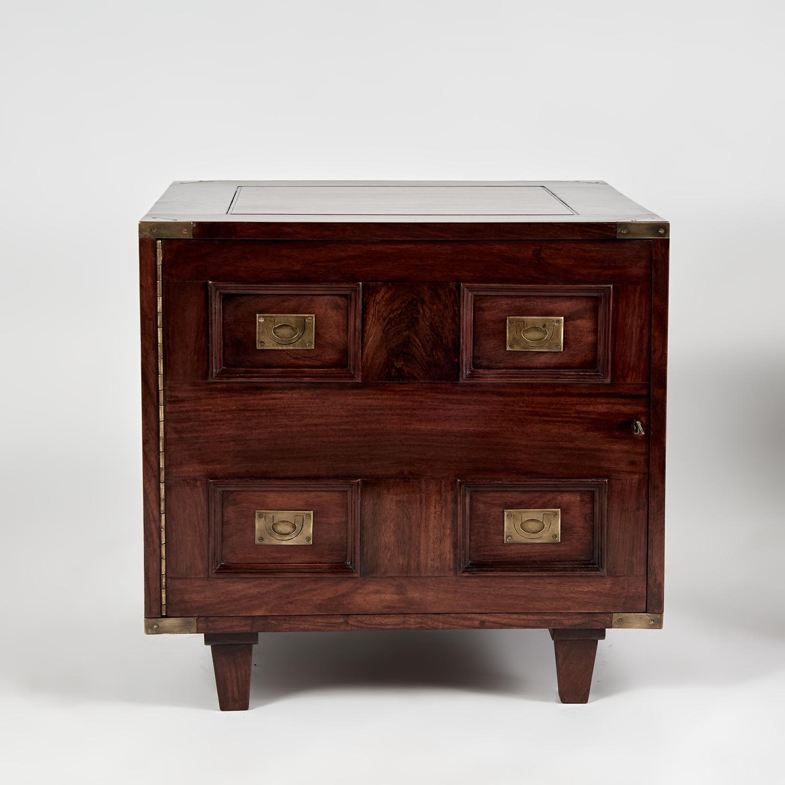 Standout pair of British colonial style Anglo Indian cabinet stands crafted in mahogany with paneled top, sides and front, campaign brass hardware, hinged doors open to plenty of storage space and tapered feet. 