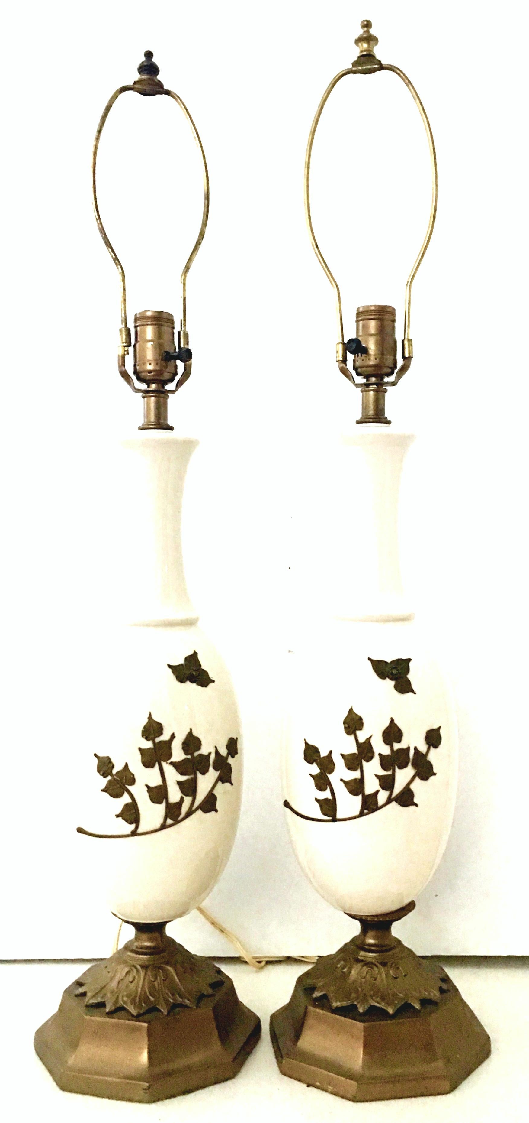 Mid-20th century pair of Art Nouveau ceramic glaze and bronze ostrich egg form table lamps. This incredibly and unique pair of lamps feature an off white ground with hand applied abstract formed raised bronze floral motif. Mounted on double bronze
