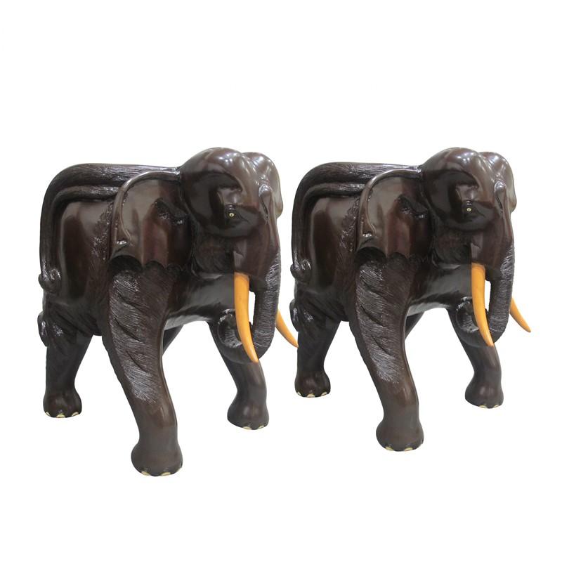 Un impresionante par de sillas con forma de elefante. Cada silla está tallada a mano en una sola pieza de madera dura con asiento excavado. Estas excepcionales sillas son muy cómodas y están bellamente detalladas con ojos pintados, uñas y colmillos