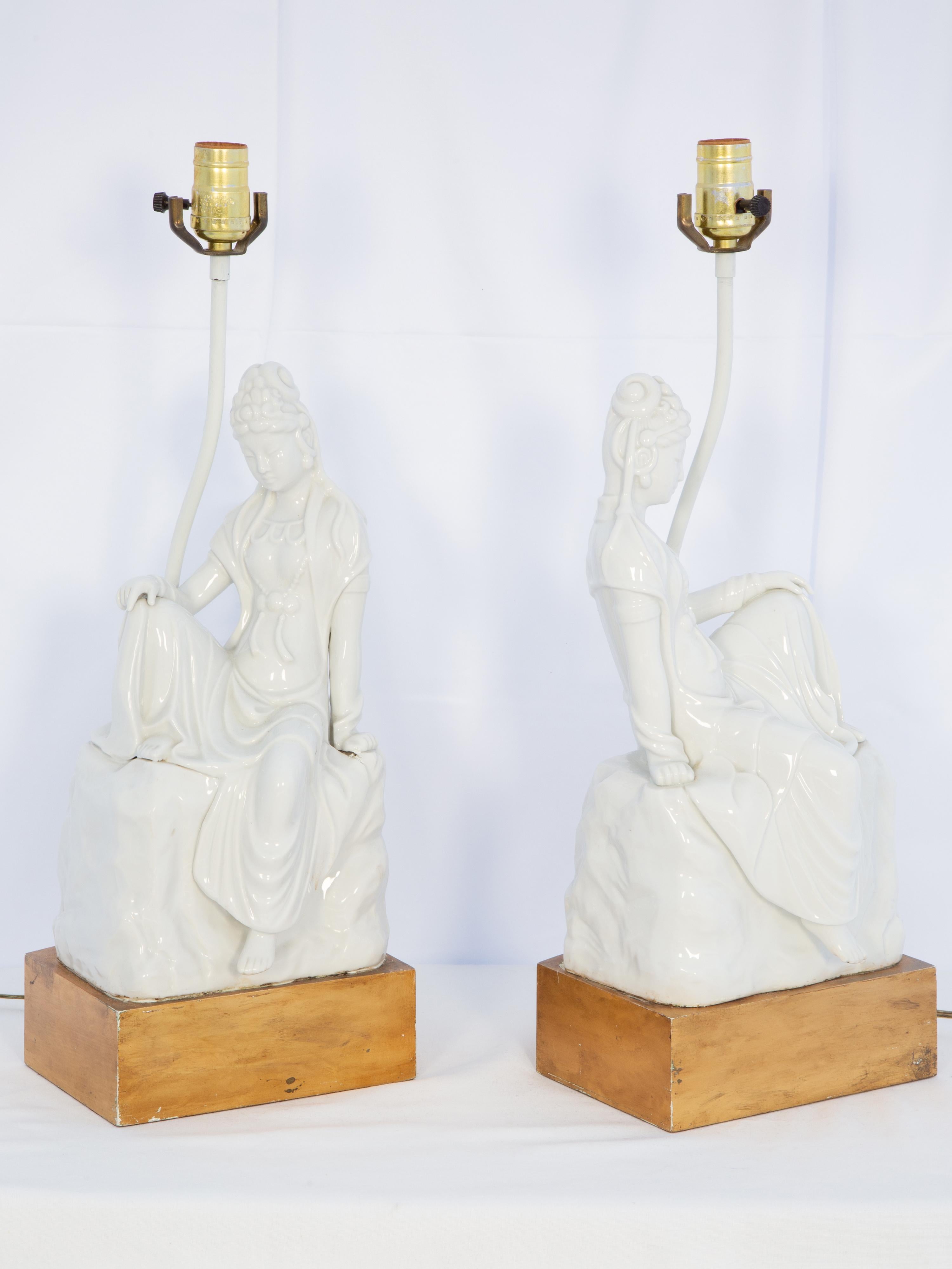 Gegenüberliegendes Paar figuraler Blanc-de-Chine-Lampen mit je einer Kwan-Yin-Figur in liegender, sitzender Pose, auf vergoldetem Sockel stehend. 

Lager-ID: D4179