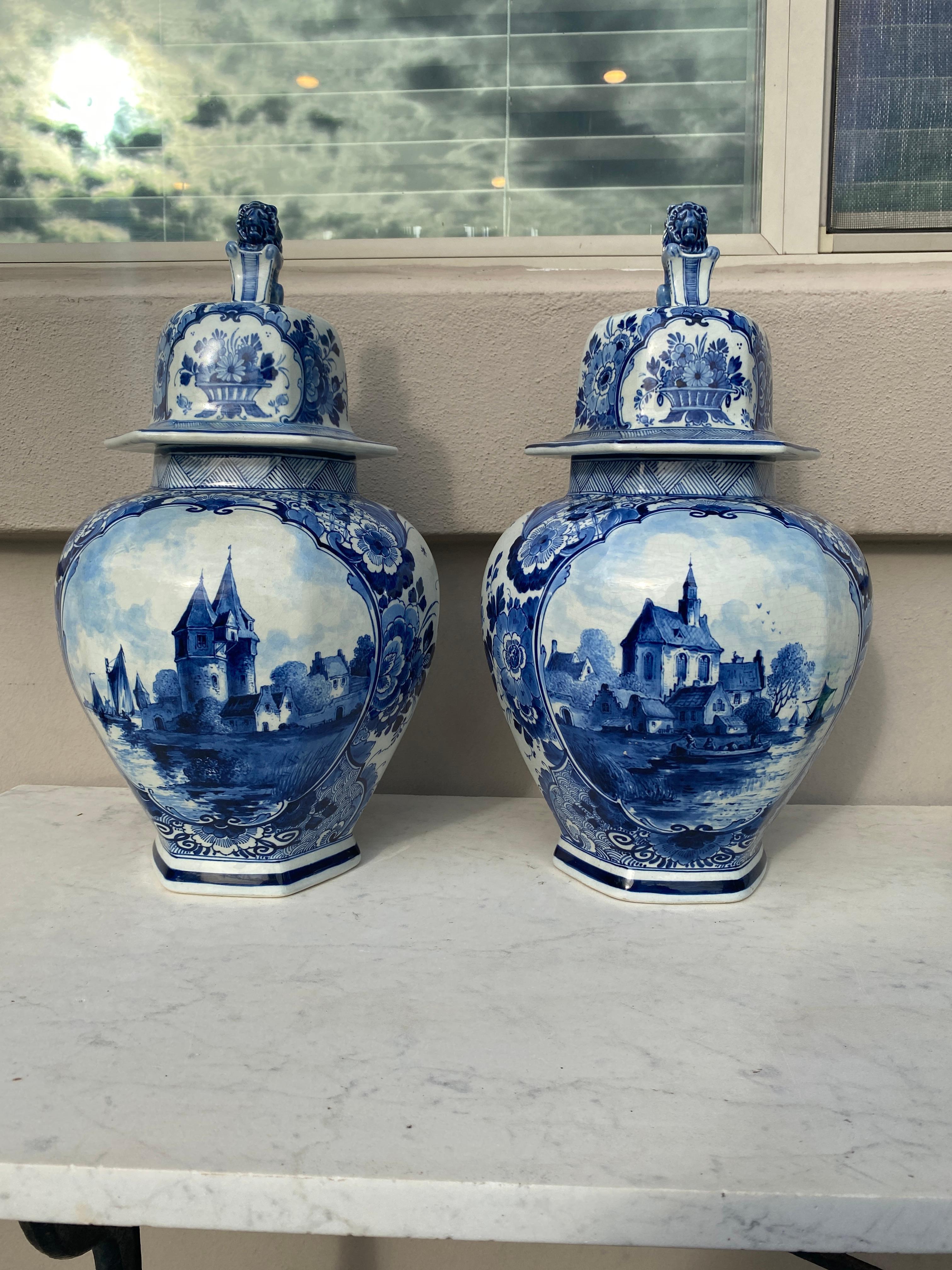 Mid-Century Pair of Blue & White Delft Ginger Jars.
lids with lion-dog finials.
Scene of church,castle and buildings , on the back flowers..