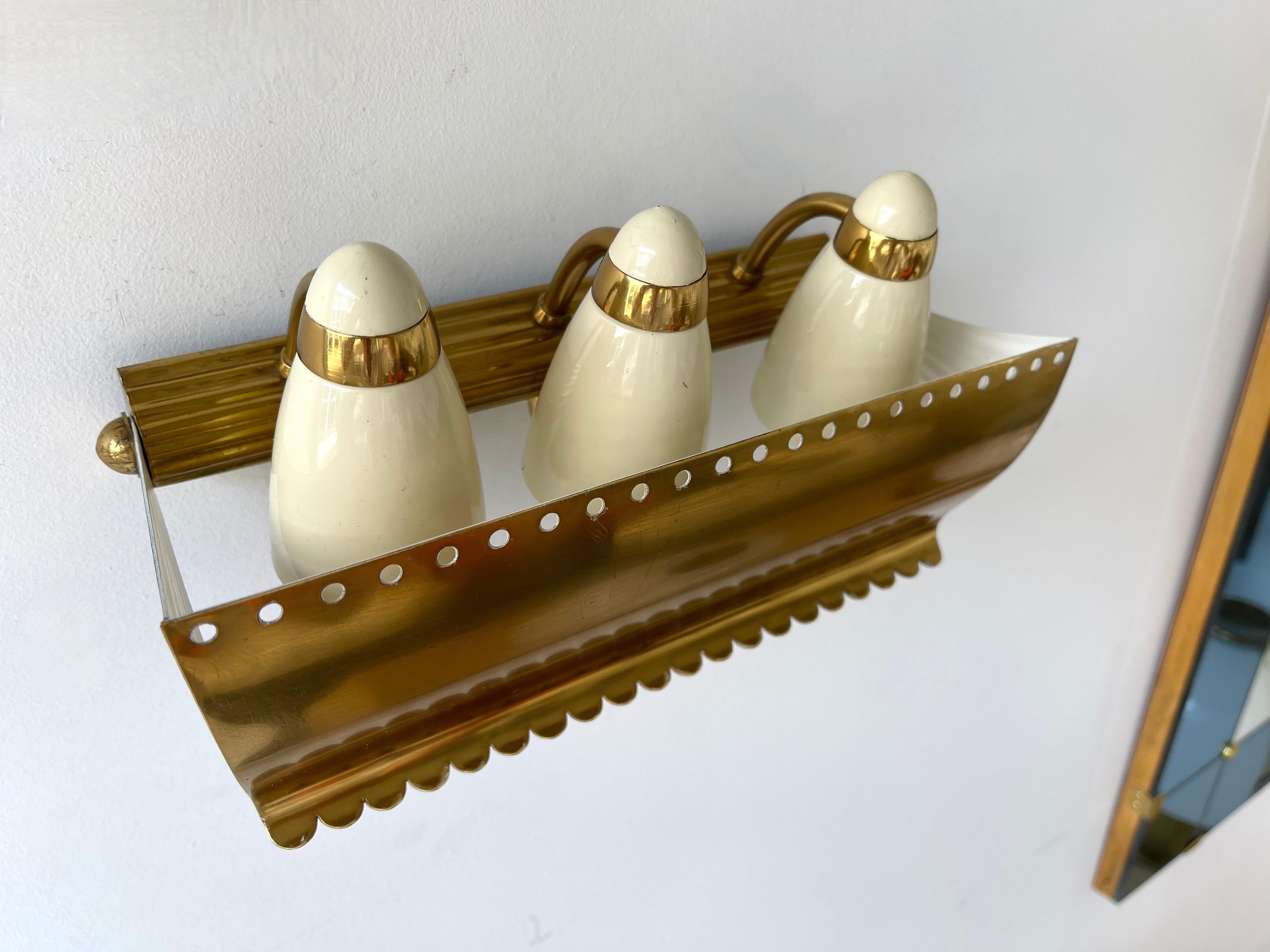 Mid Century pair of brass and white cream enamelled metal wall lights lamps sconces. Slight differences of patina and on the back plates. In the mood of Angelo Lelii, Esperia, Stilnovo, Arteluce, Arredoluce.