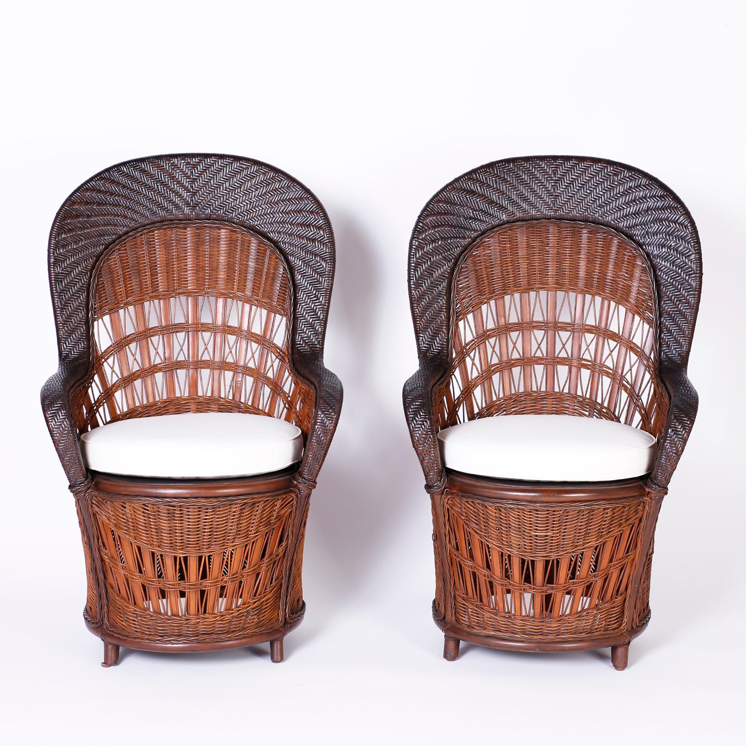 Unusual pair of British Colonial peacock chairs crafted in wicker and reed with several weave patterns, a two-tone finish and a unique compact form.
