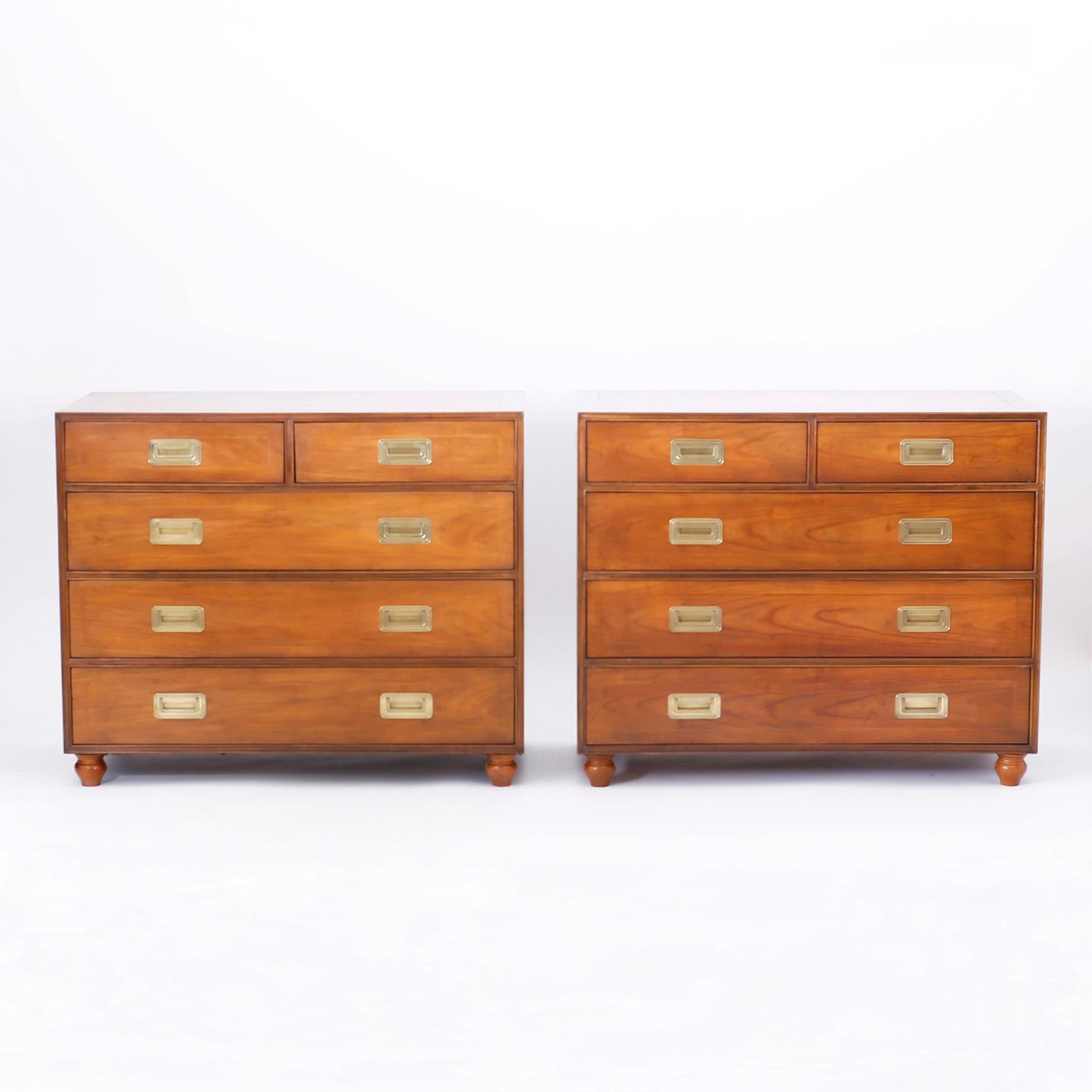 Pair of Campaign style chests crafted in well grained walnut with a sleek no nonsense form, brass hardware and turned feet. Perfect combination of Classic and modern and signed Baker Furniture in a drawer.