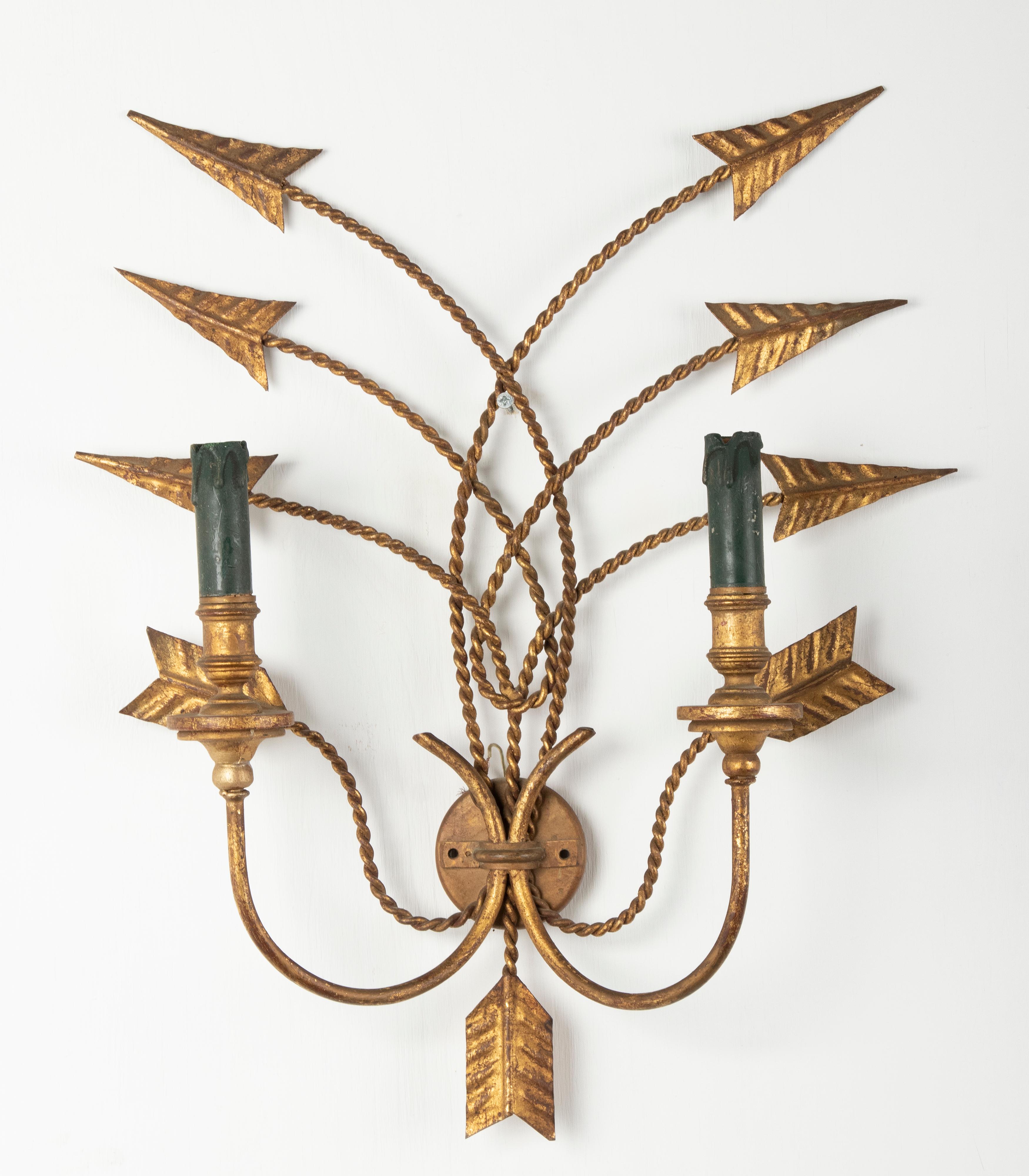 A stylish pair of wall lights, made off metal with a gold patina finish. The arrows-shaped are intertwined. The candle holders are made of moulded resin. All lamps have E14 fittings. The lamps are wired and both in working order. Made in France,