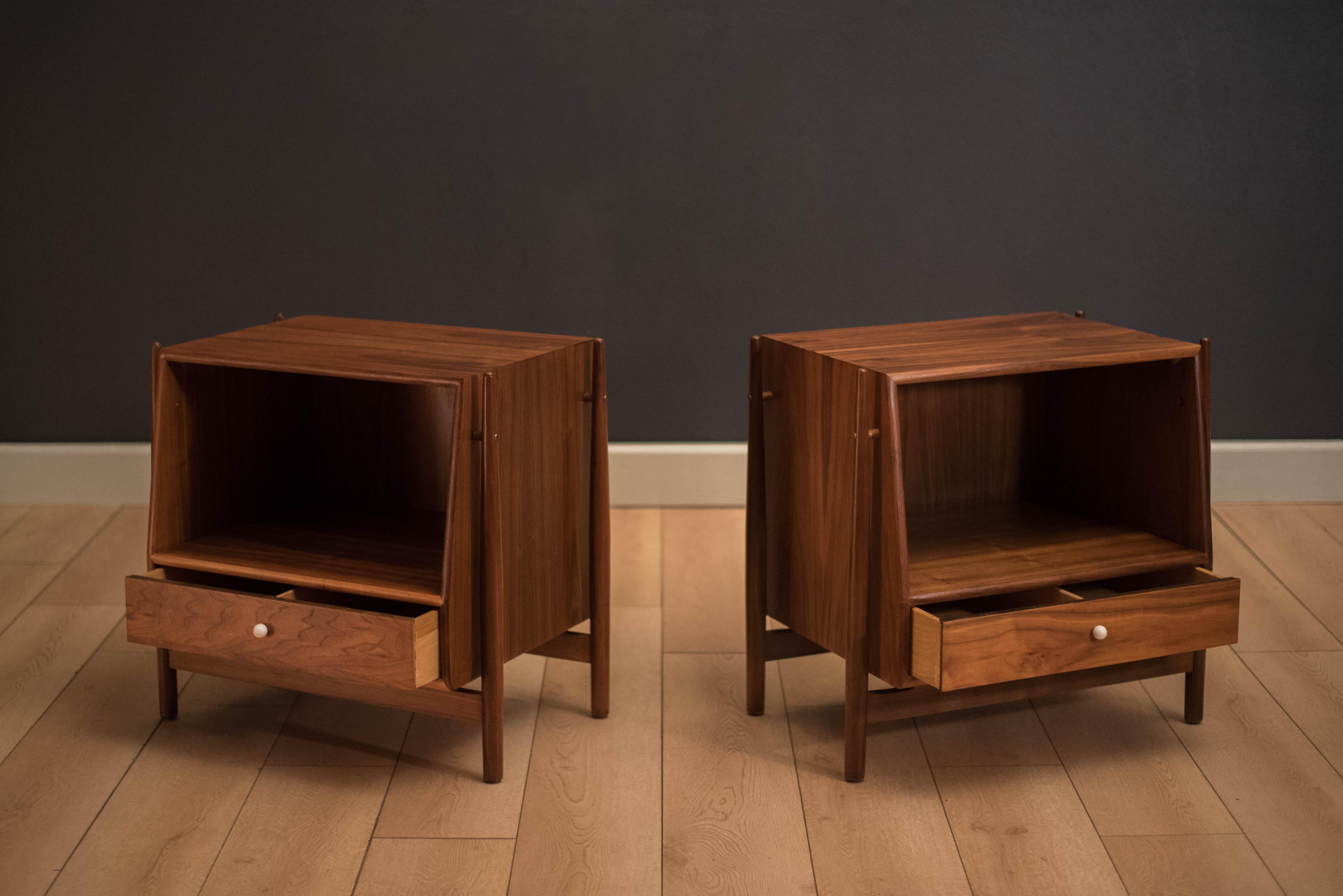 Mid-Century Modern pair of nightstands designed by Kipp Stewart and Stewart MacDougall in walnut. This set includes one drawer on each bedside table and an open storage display shelf. Price is for the pair.